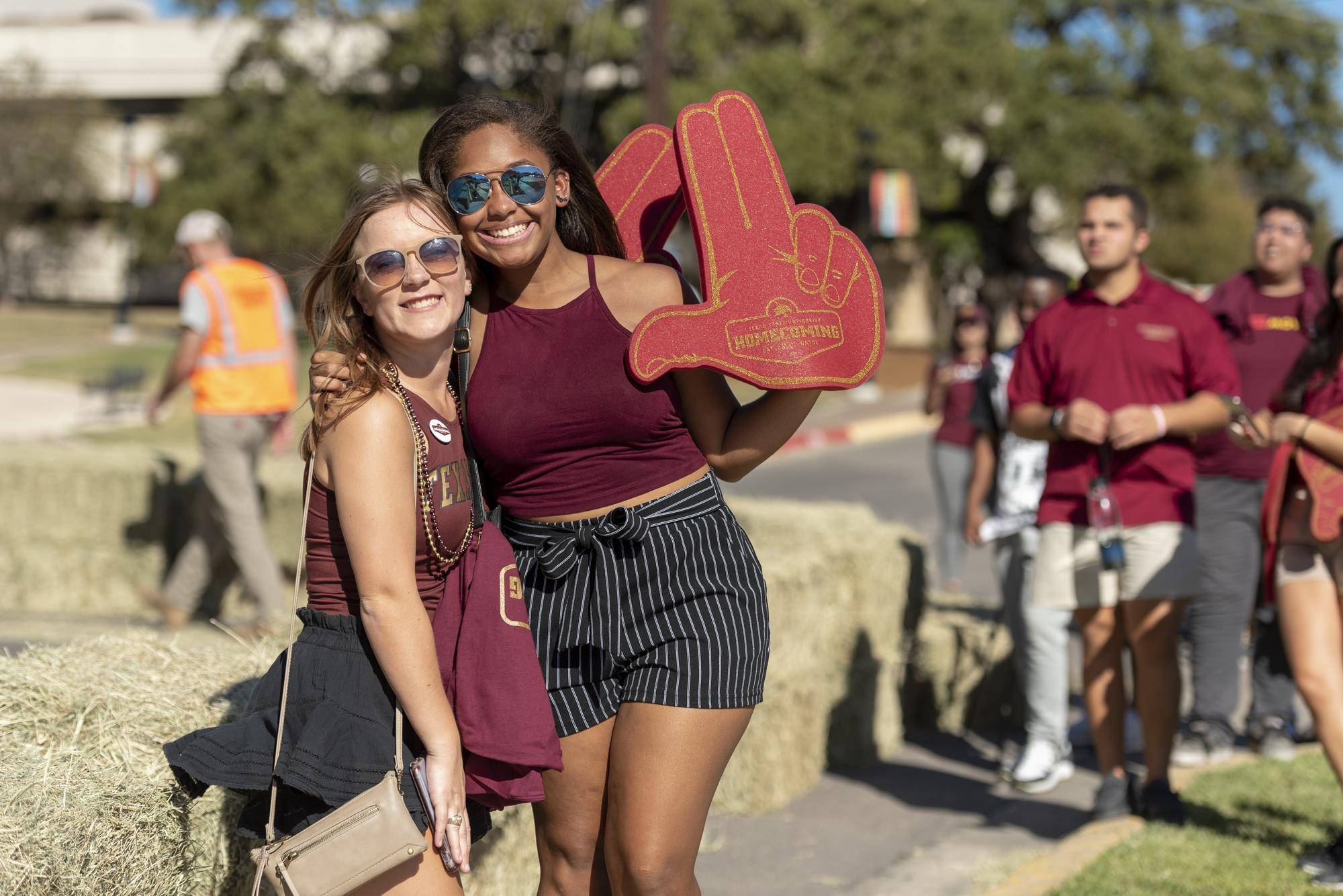 two women holding up txst hand signs