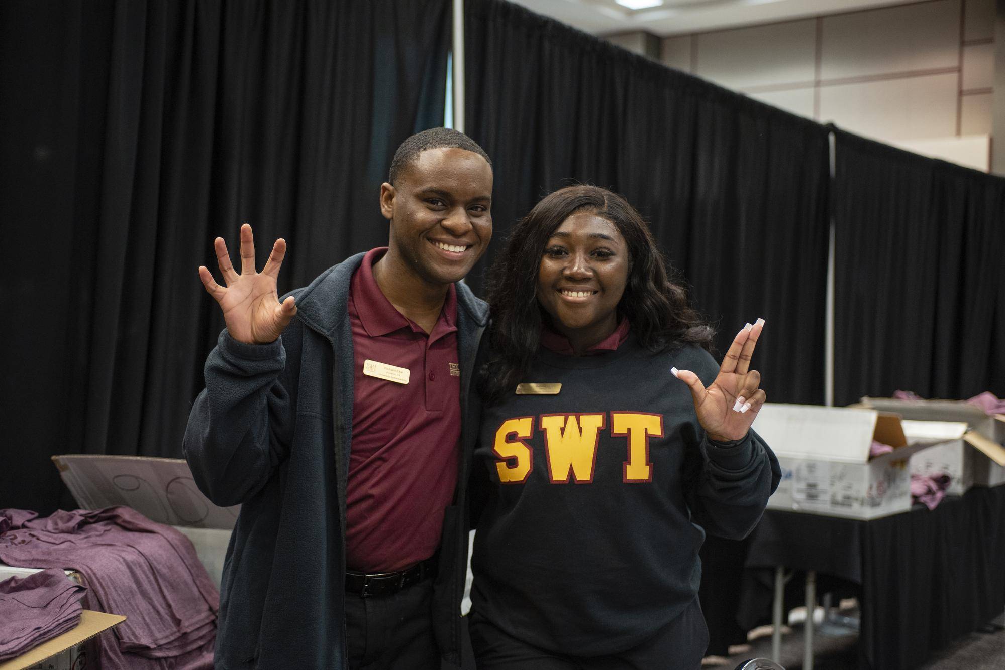 man and woman holding up txst hand signs