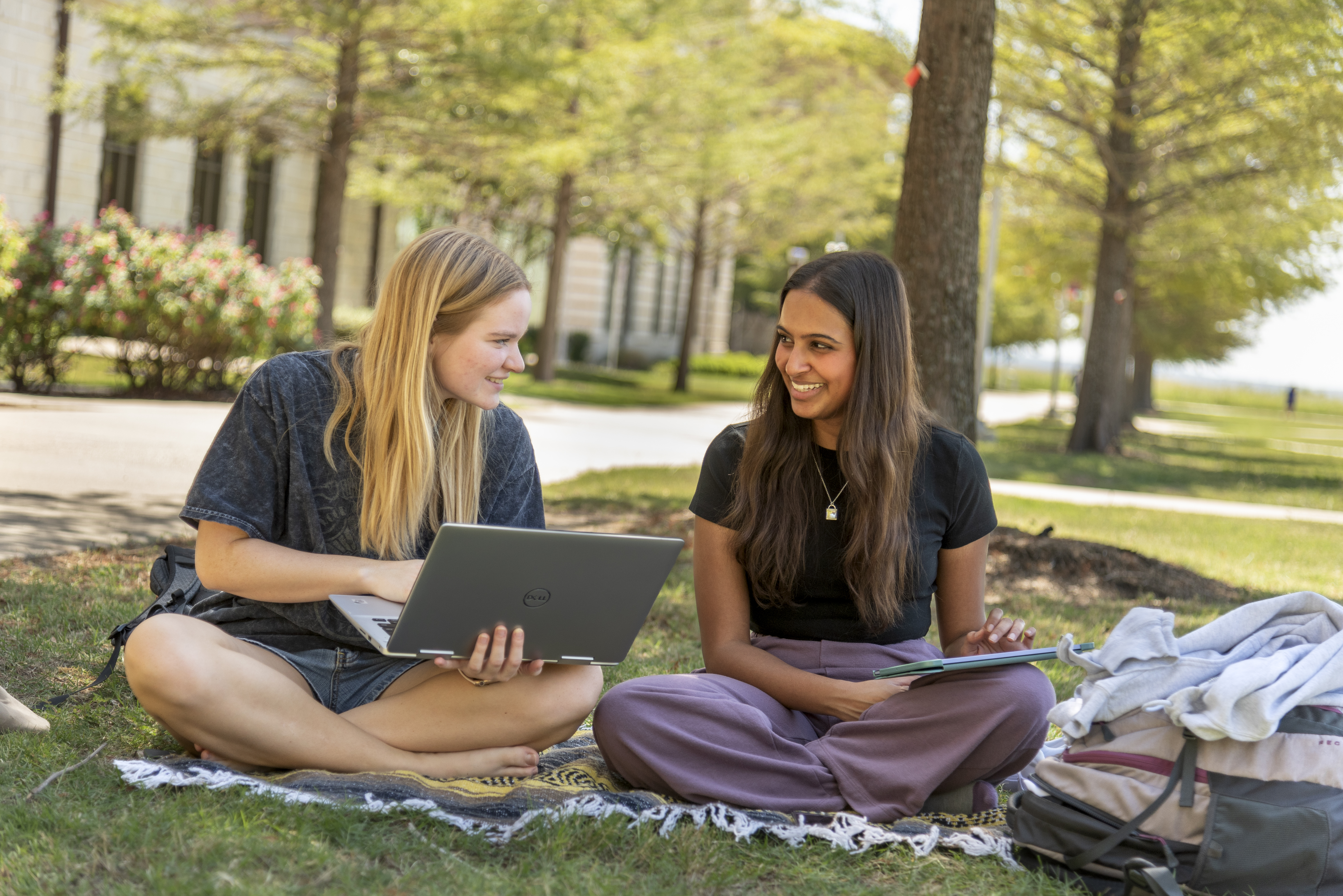 An image of two students sitting outside, talking to each other.
