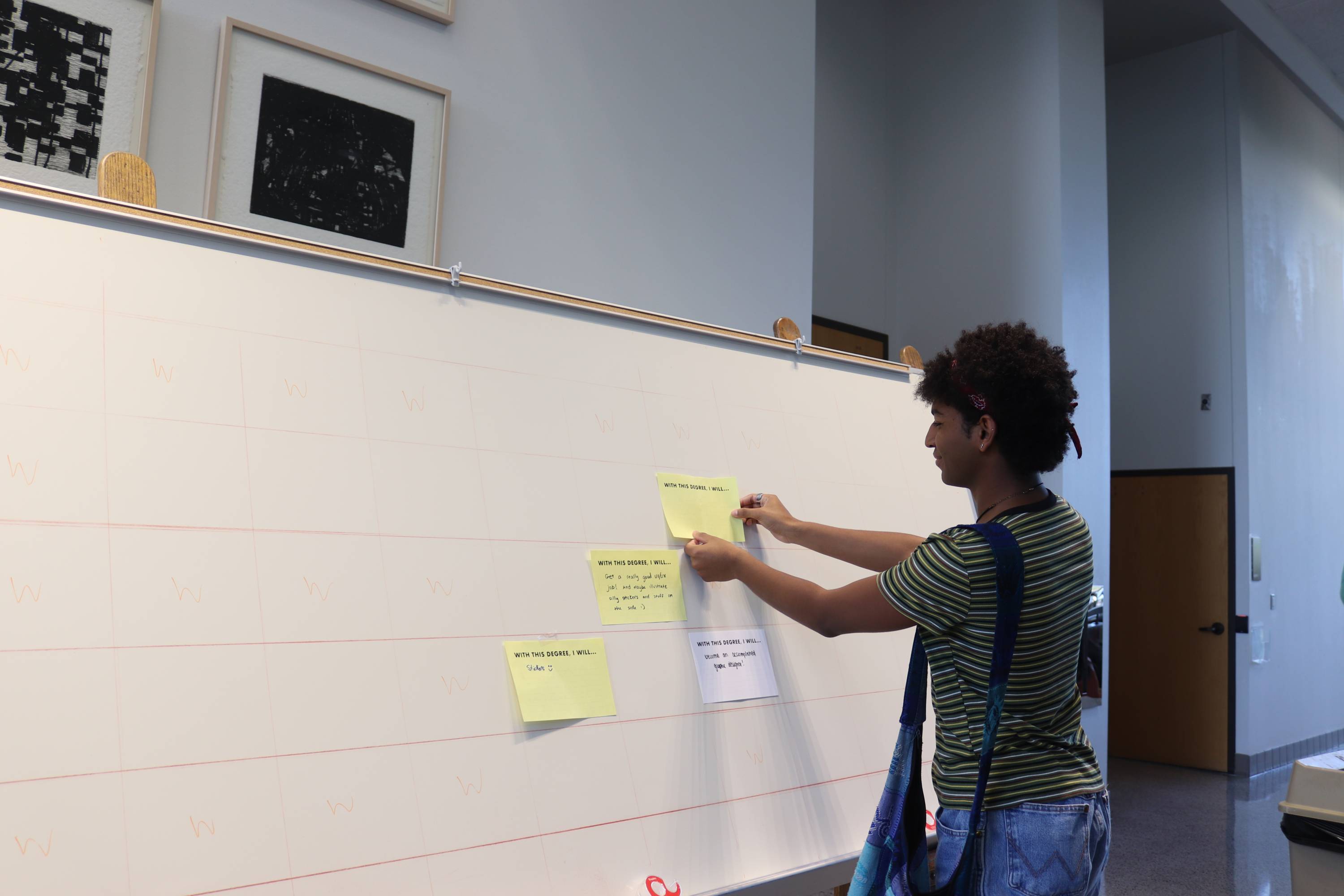 Student putting paper on a white board