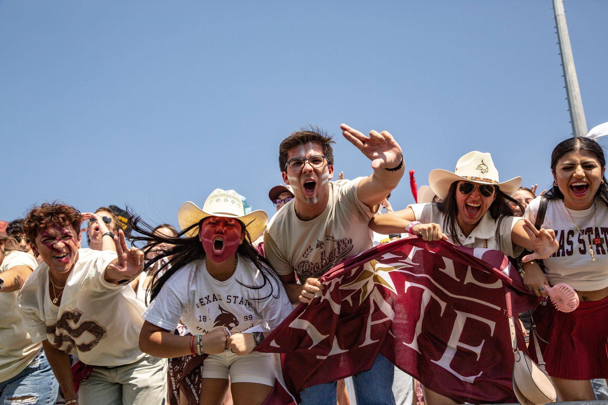 large crowd of students cheering in the stands during a football game