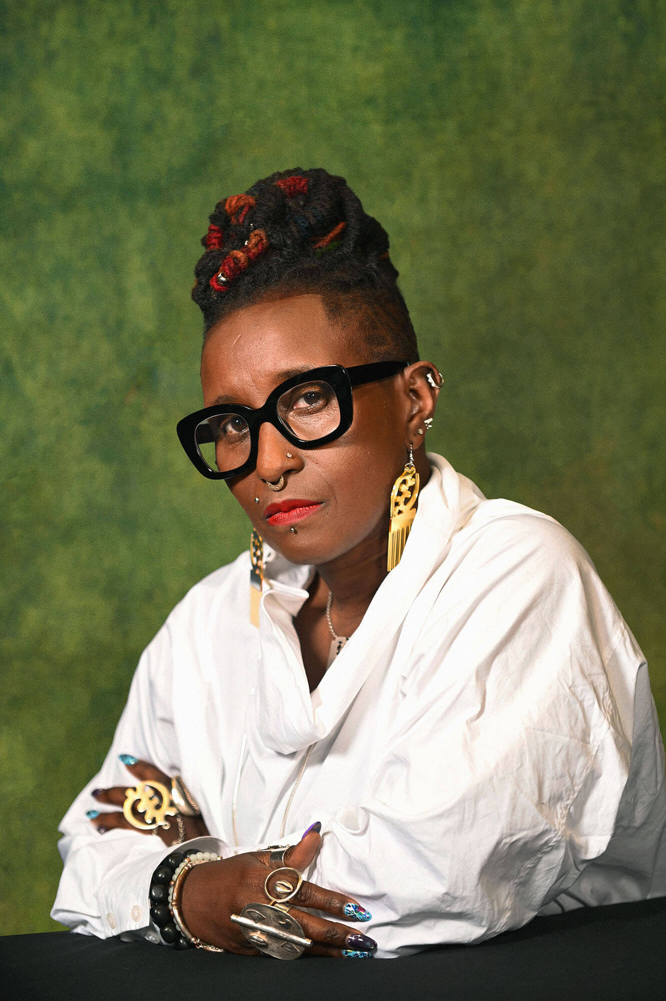 Malika Booker sat in front of a green background