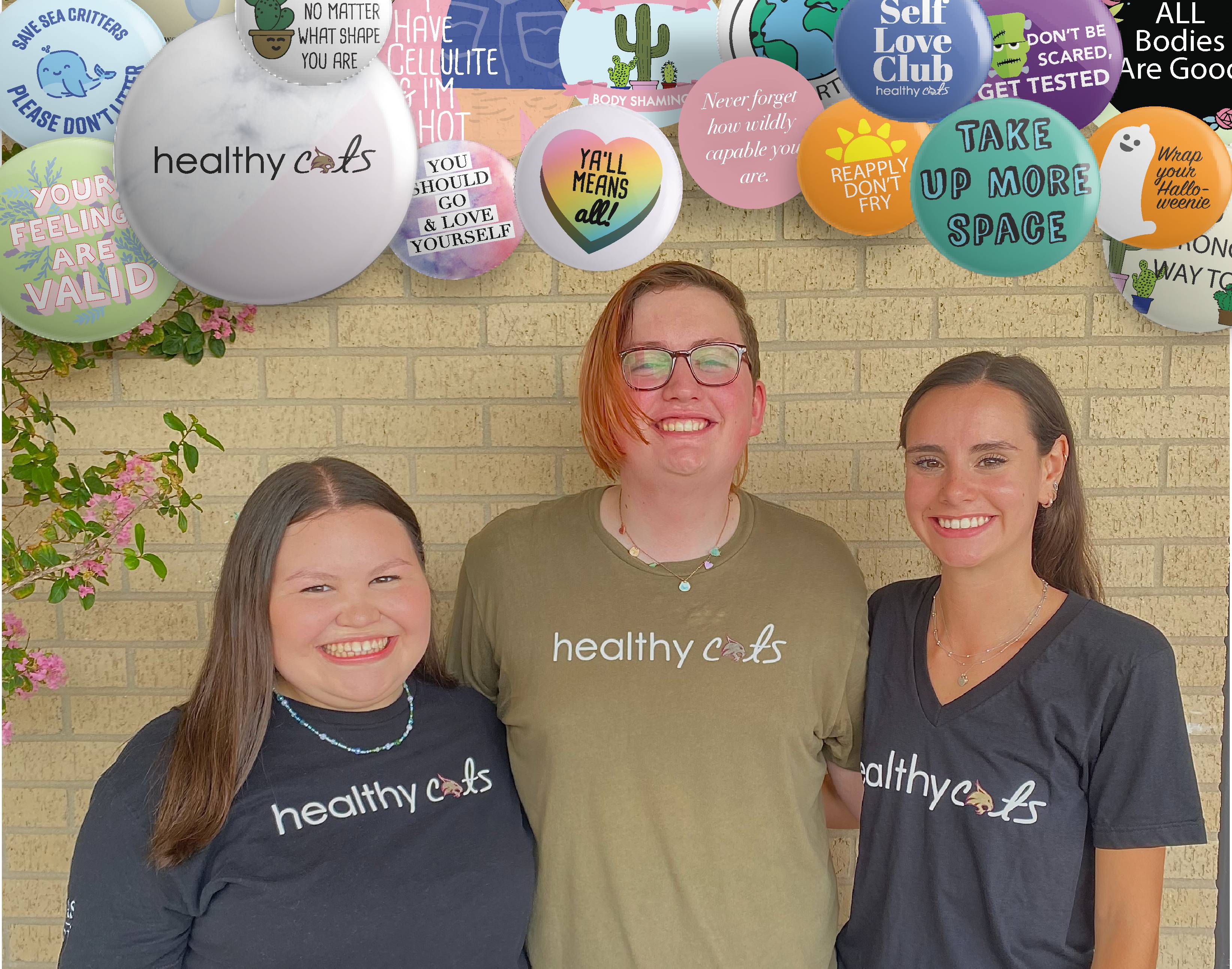 A trio of HealthyCats representatives stands in front of a wall, smiling.