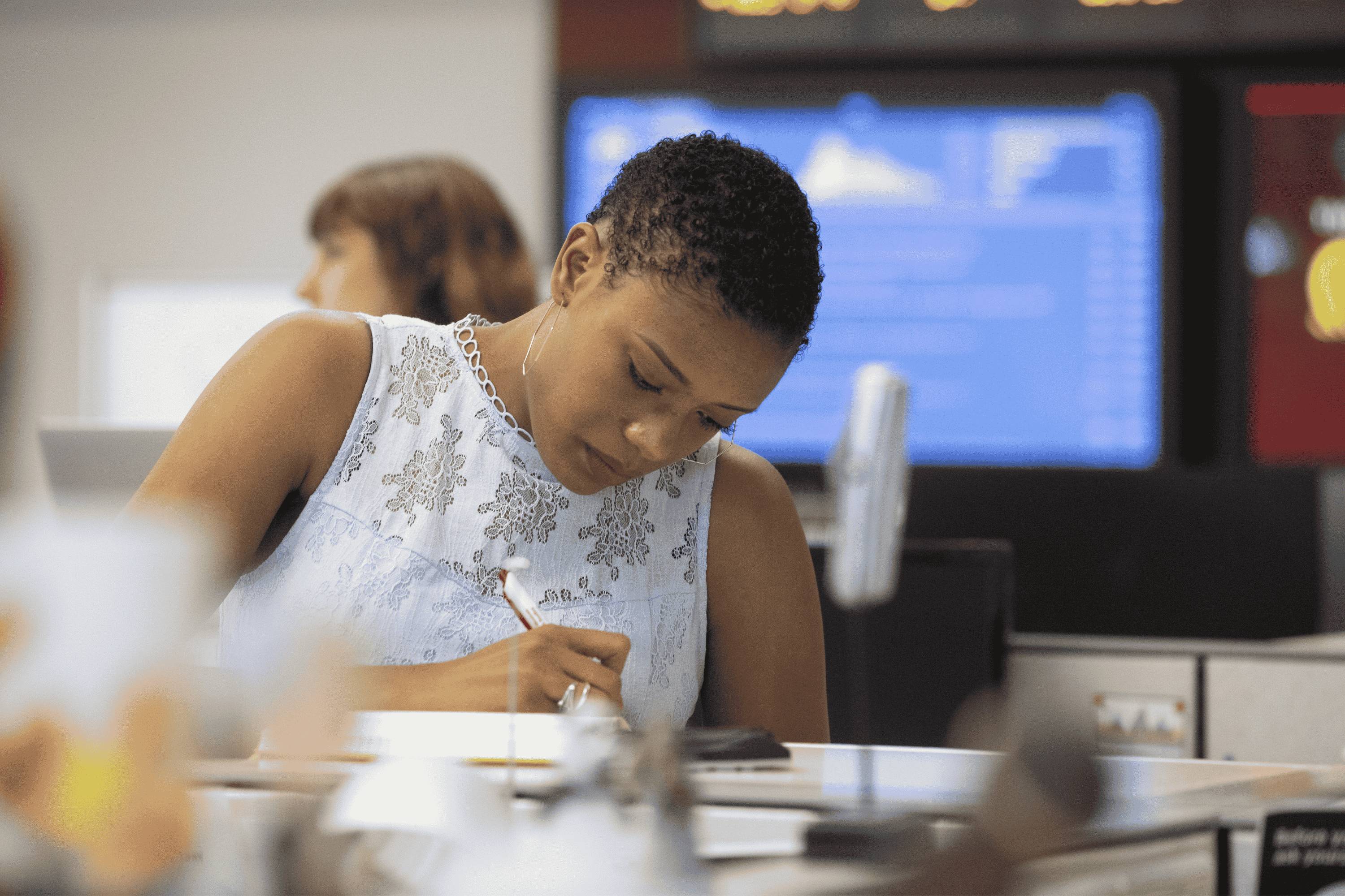 A student looking at her notes and writing.