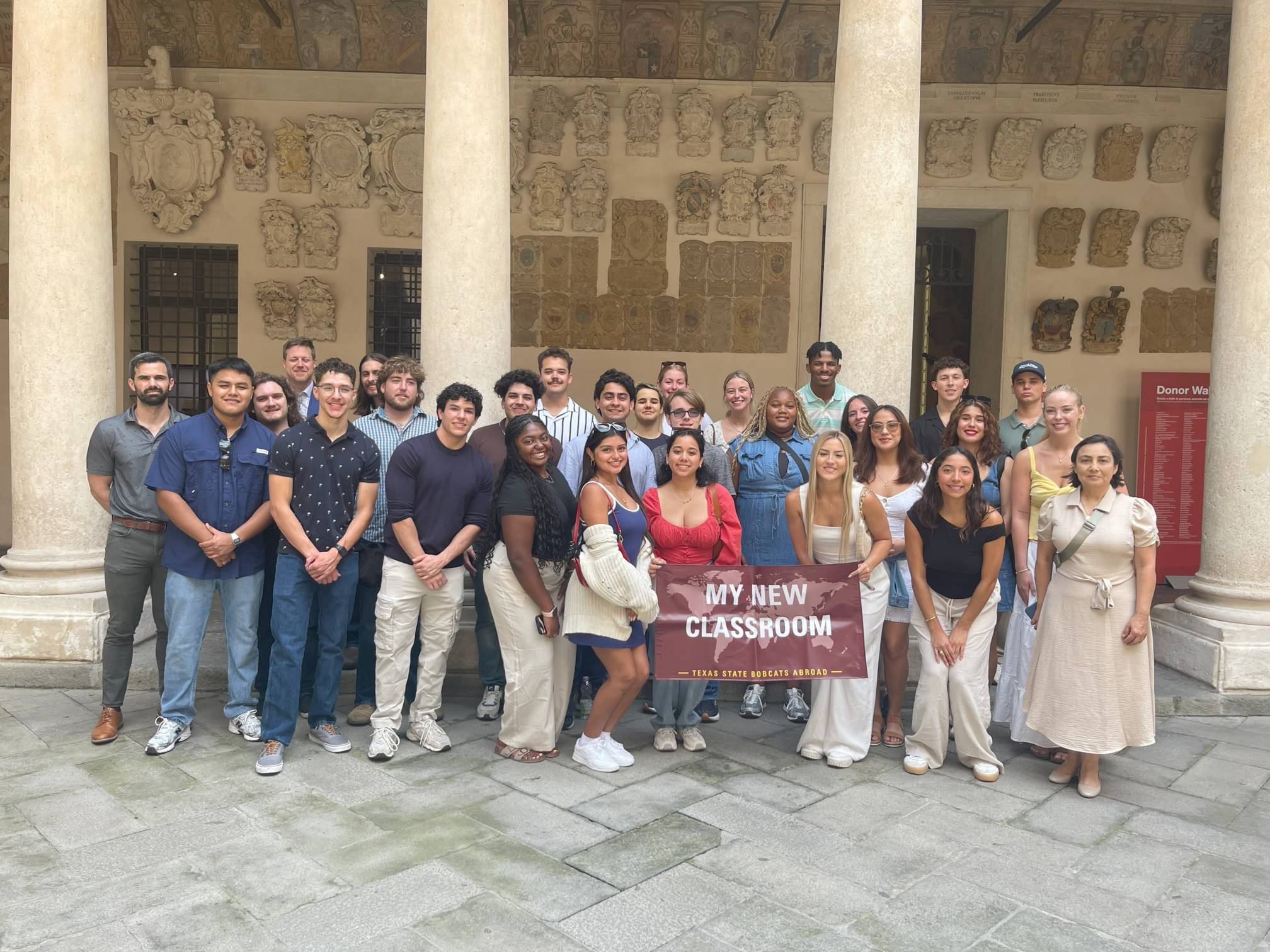 student group standing in front of Plazzo Bo with Texas State banner