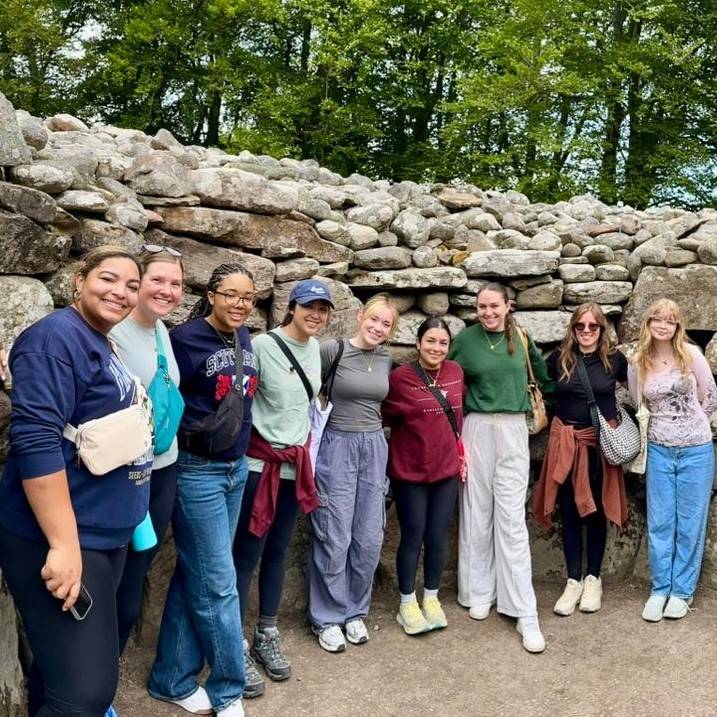 Small group of student in front of stone wall in Inverness