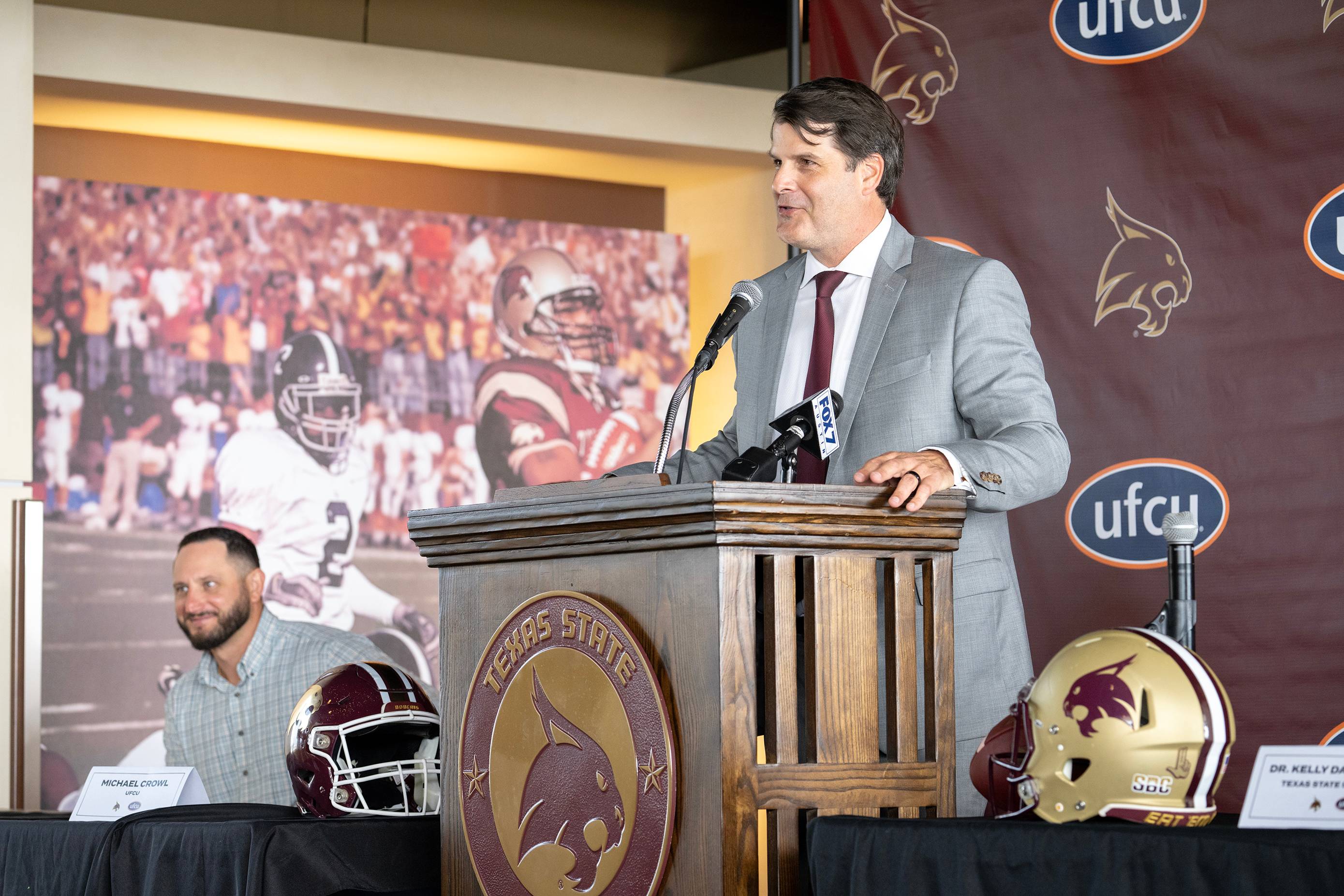 man in gray business suit speaking behind podium