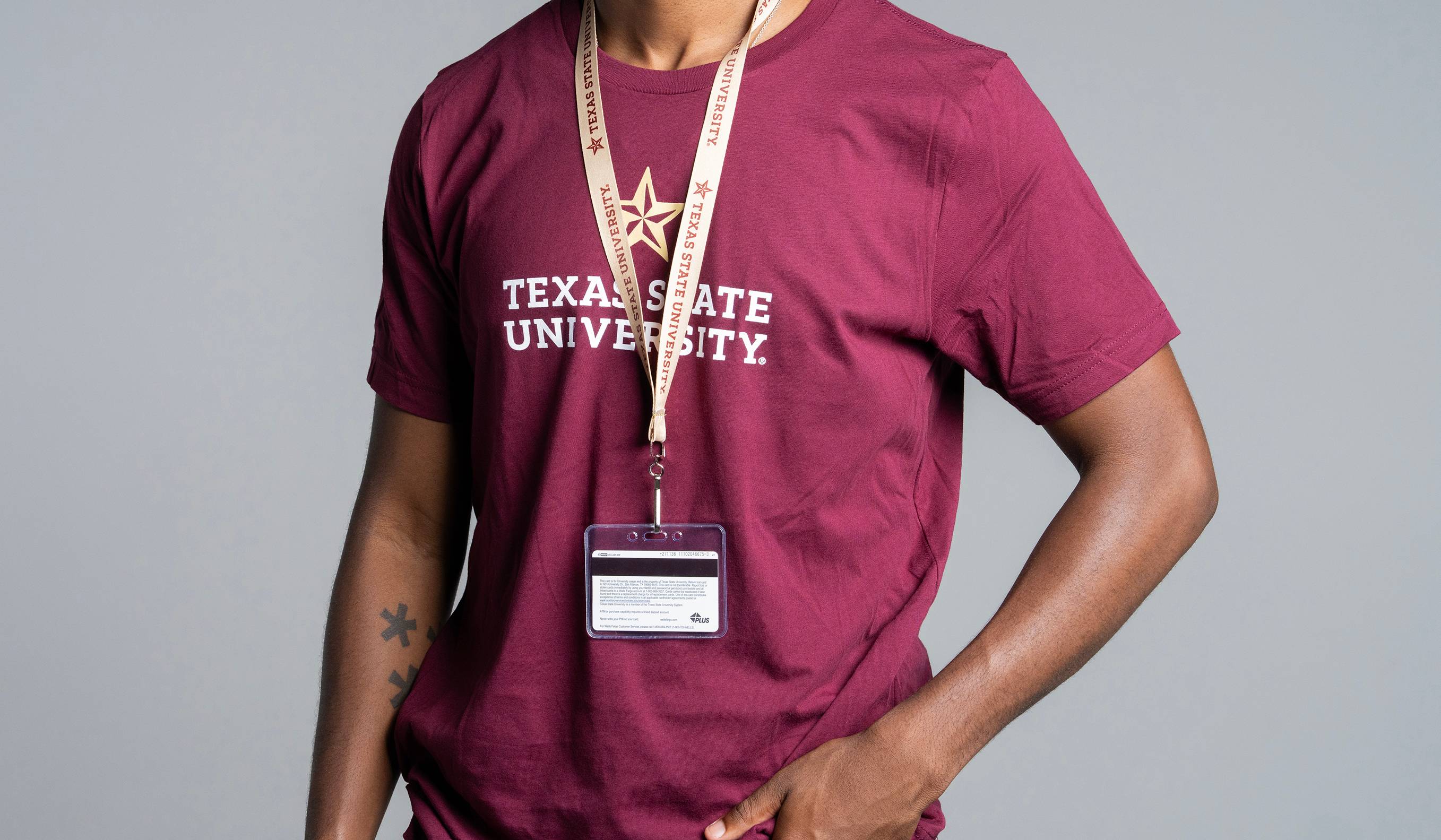man wearing a maroon shirt and gold lanyard that both read "texas state university"