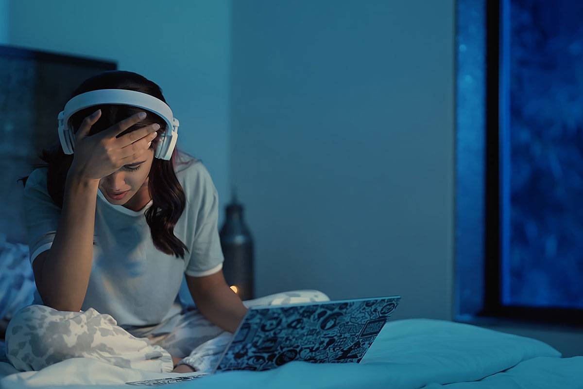 A student sits in a darkened room, looking distressed.