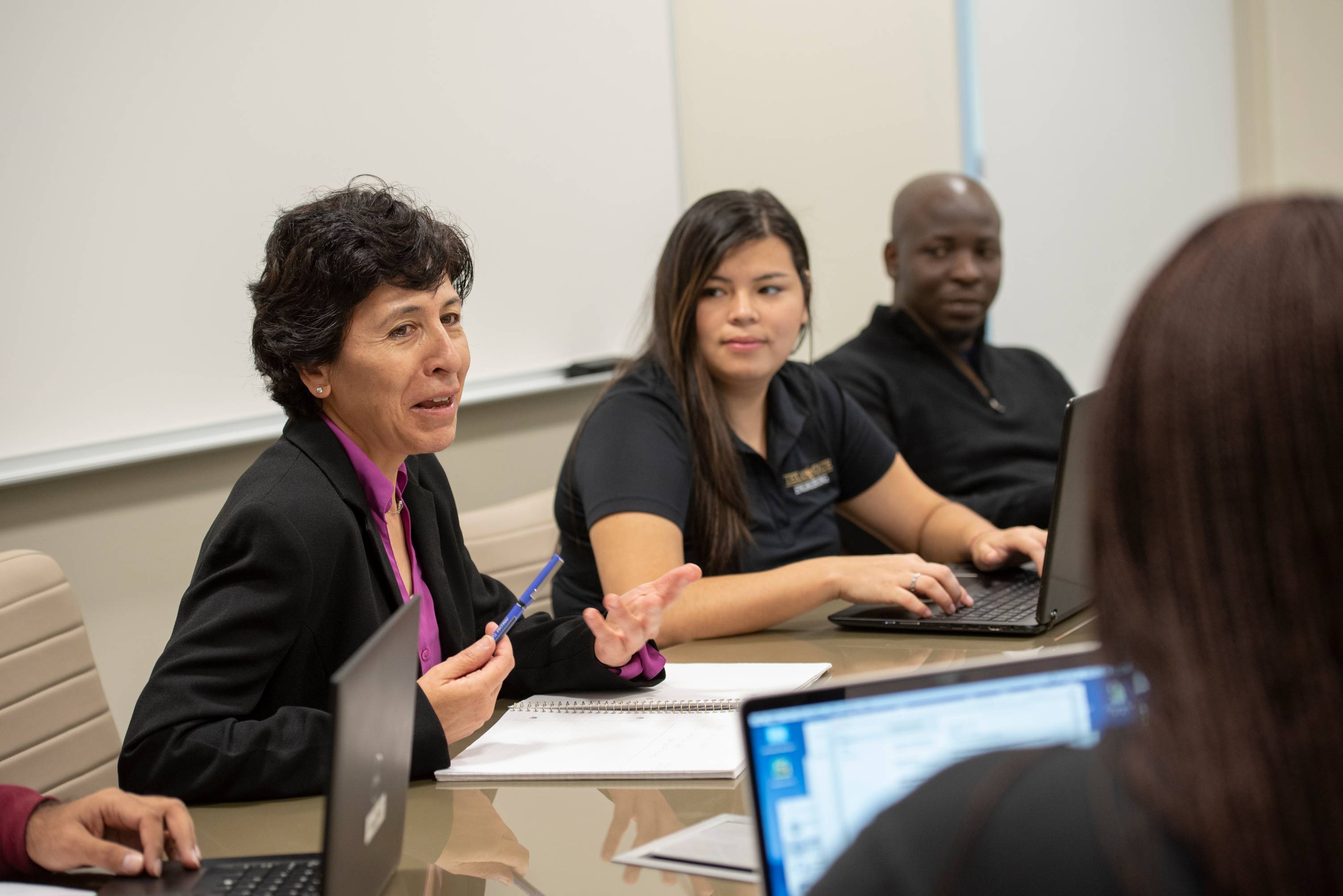 Professor talking amongst students in a meeting.