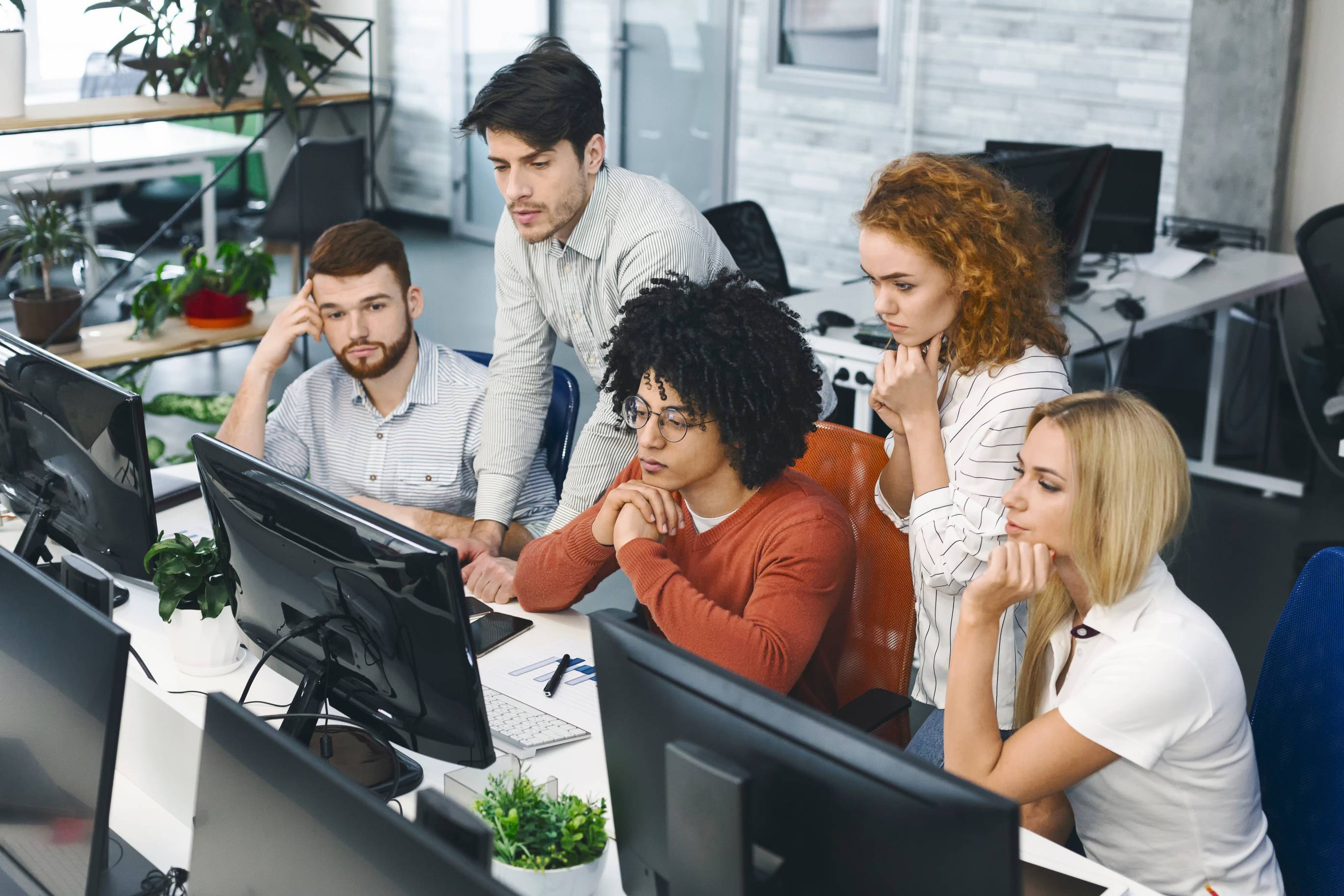 People gathered around a computer in an office. 