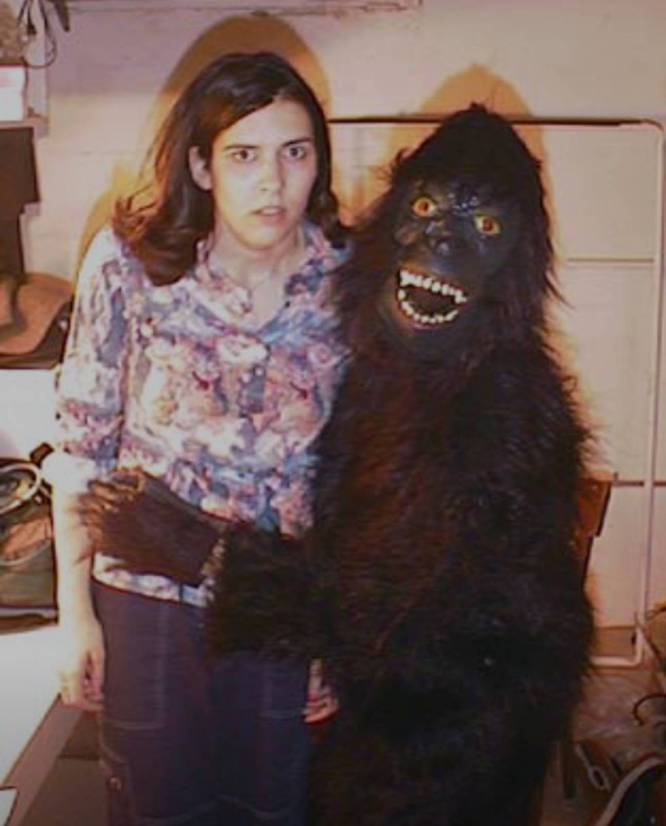 woman posing with someone in gorilla costume. she has a shocked look on her face