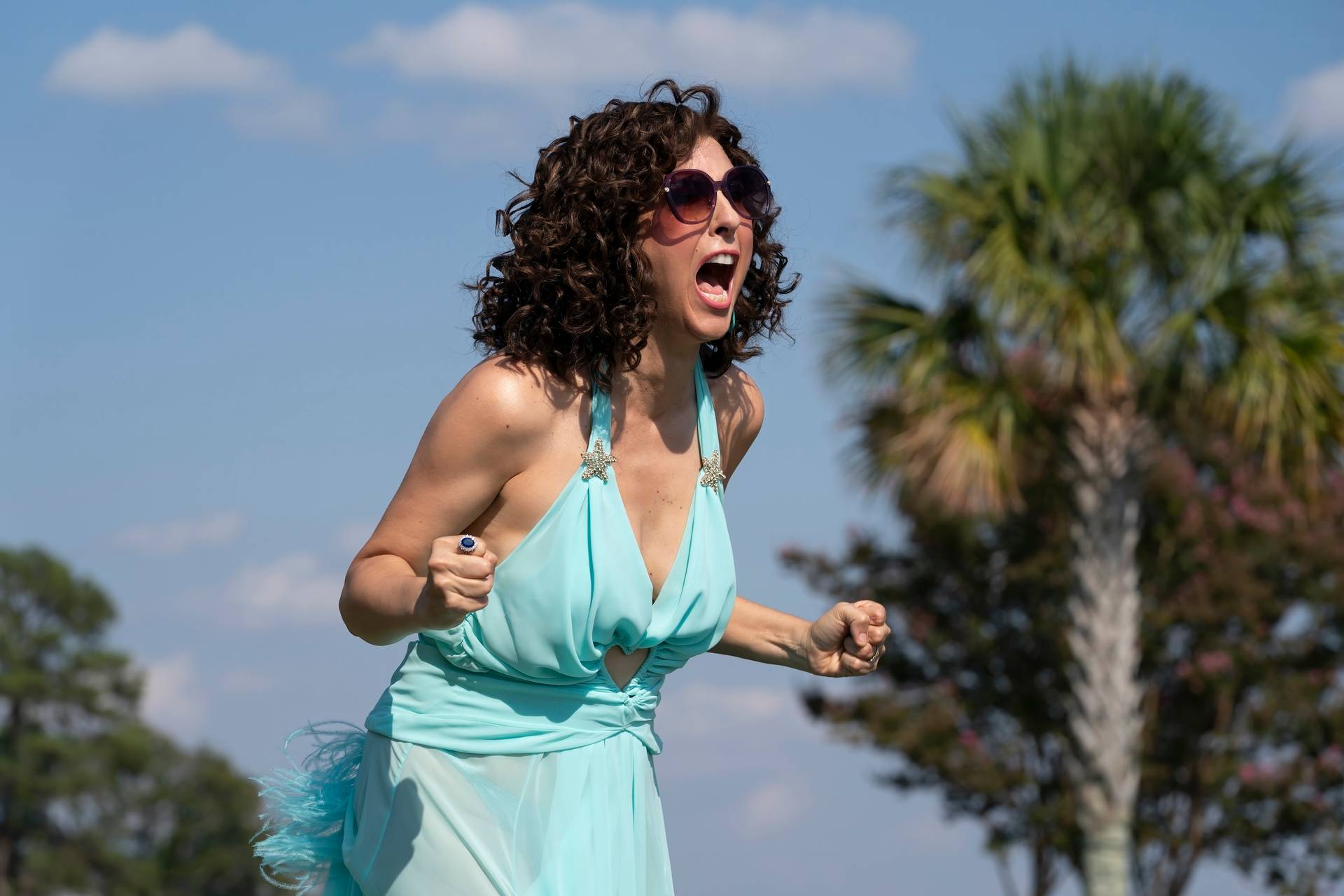 woman in blue dress screaming with clenched fists