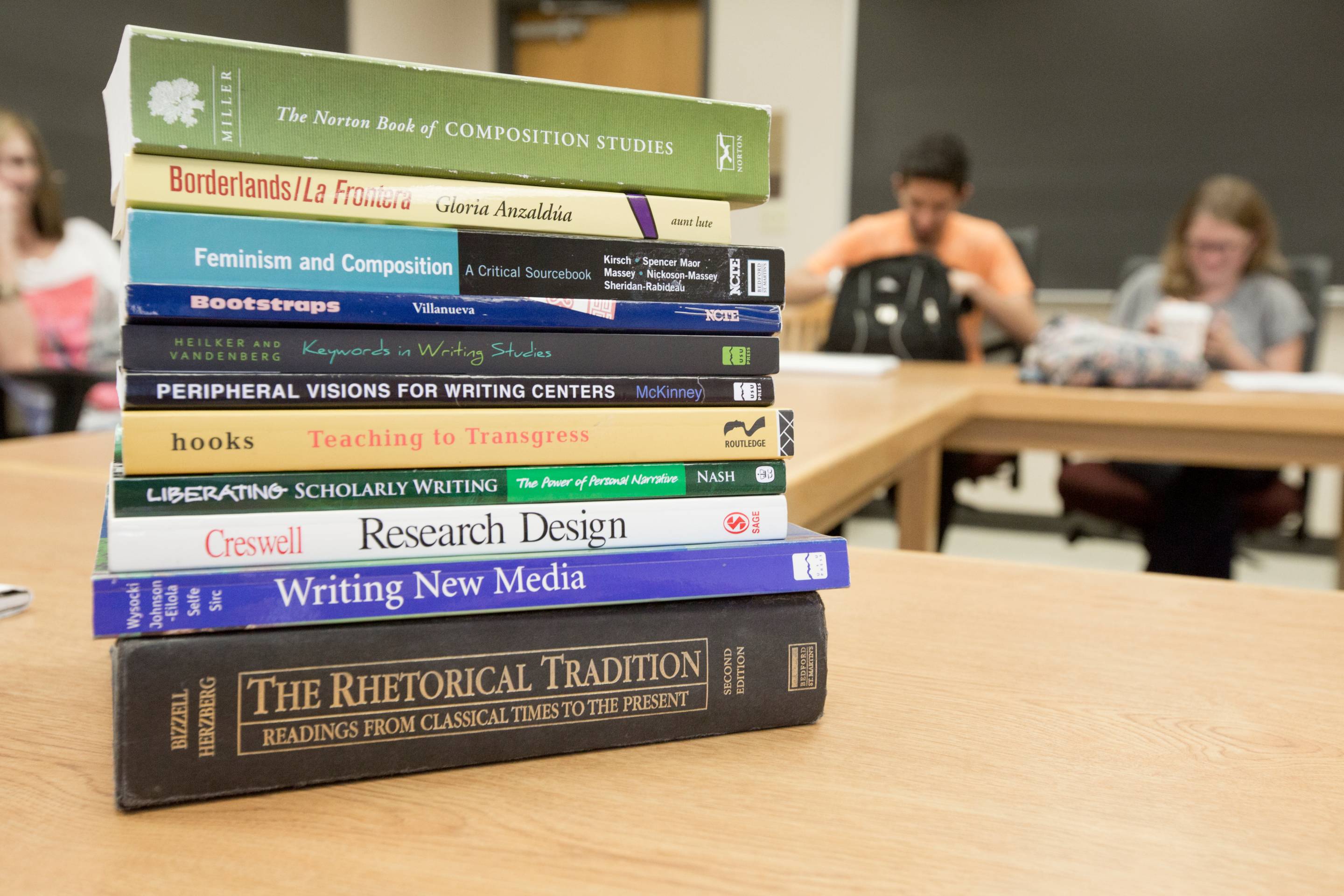 Multiple books stacked on a table in a classroom. 
