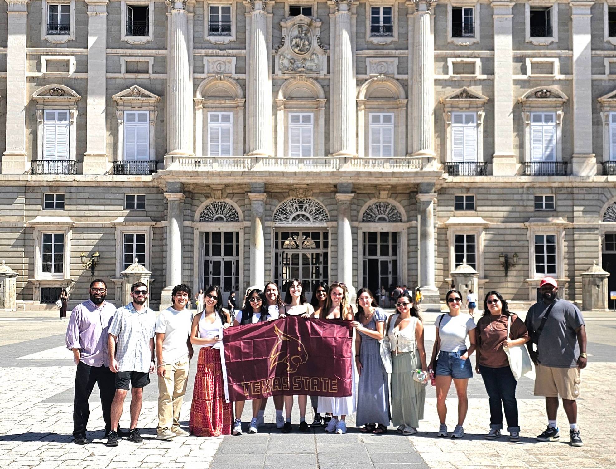 TXST students standing outside of Madrid Royal Palace with TXST flag.