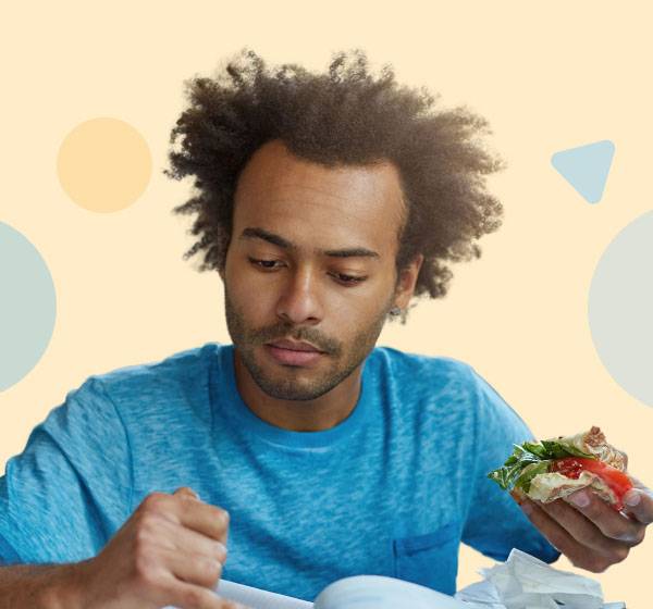 person doing homework while eating a sandwich