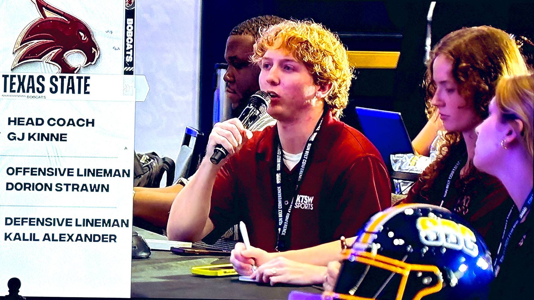 One KTSW student asks a question next to two other KTSW students.