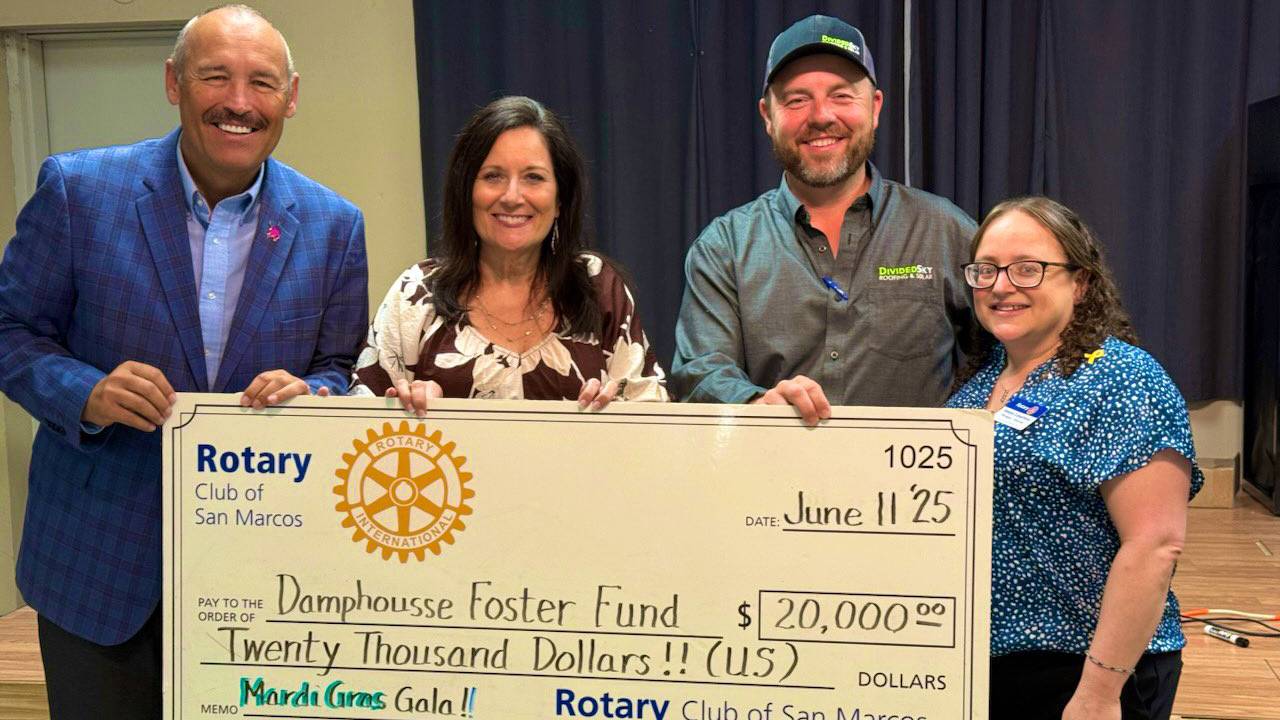 President Kelly Damphousse (left) and First Lady Beth Damphousse pose for a photo with a $20,000 check and two San Marcos Rotary Club members.