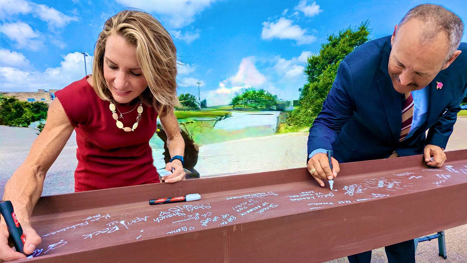 Vice President Julie Lessiter (left) and President Kelly Damphousse both sign a piece of steel.