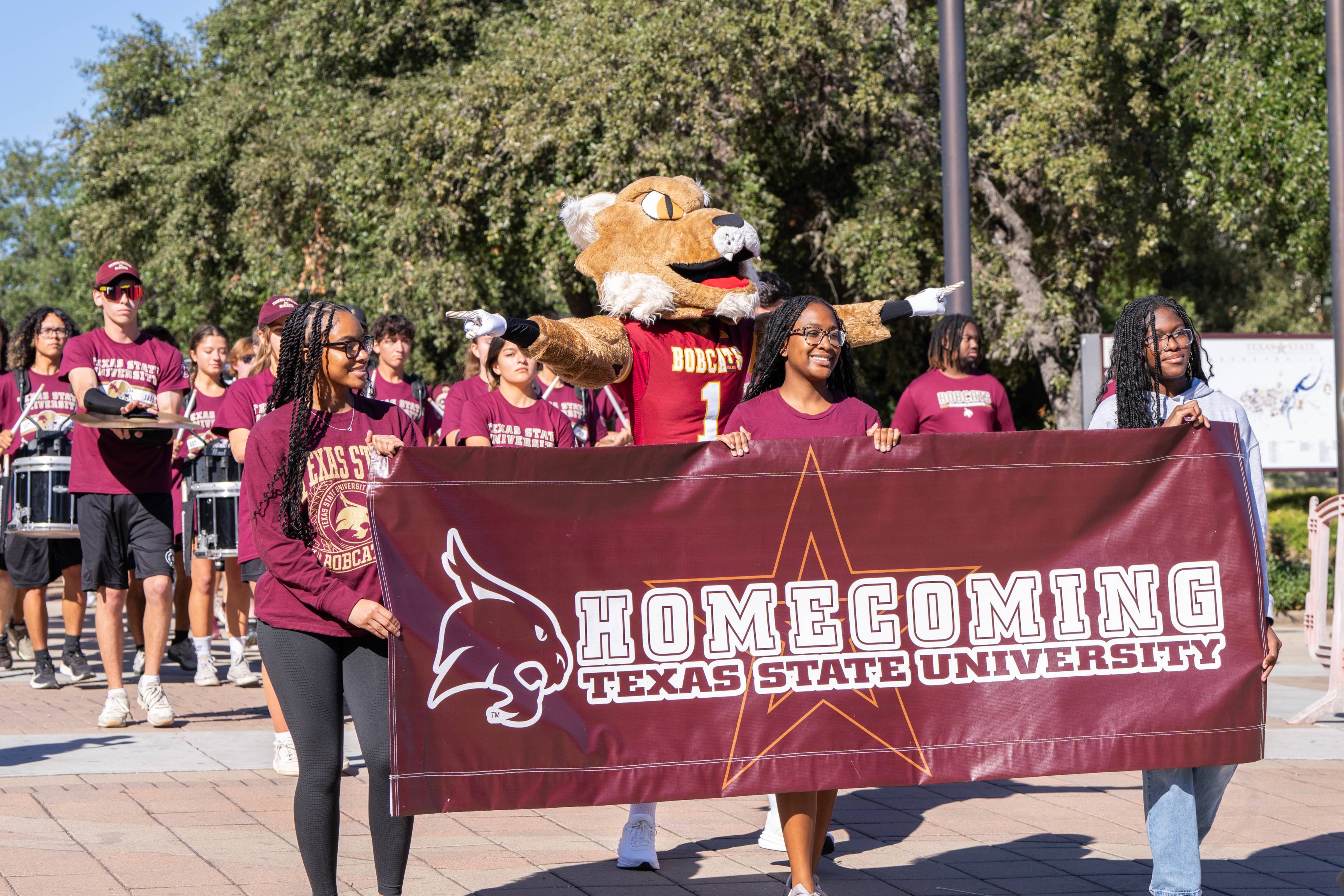 students holding a banner that has the words homecoming, texas state university