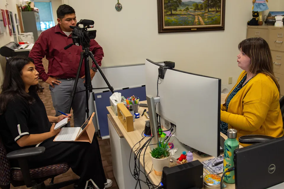 students in an office engaged in recording with a camera on a tripod