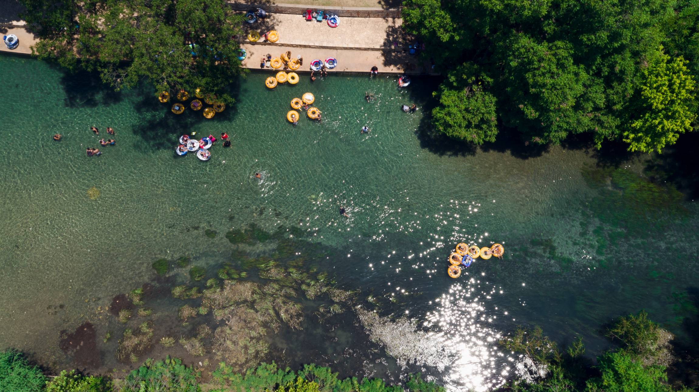 Aerial shot of river with people floating on tubes
