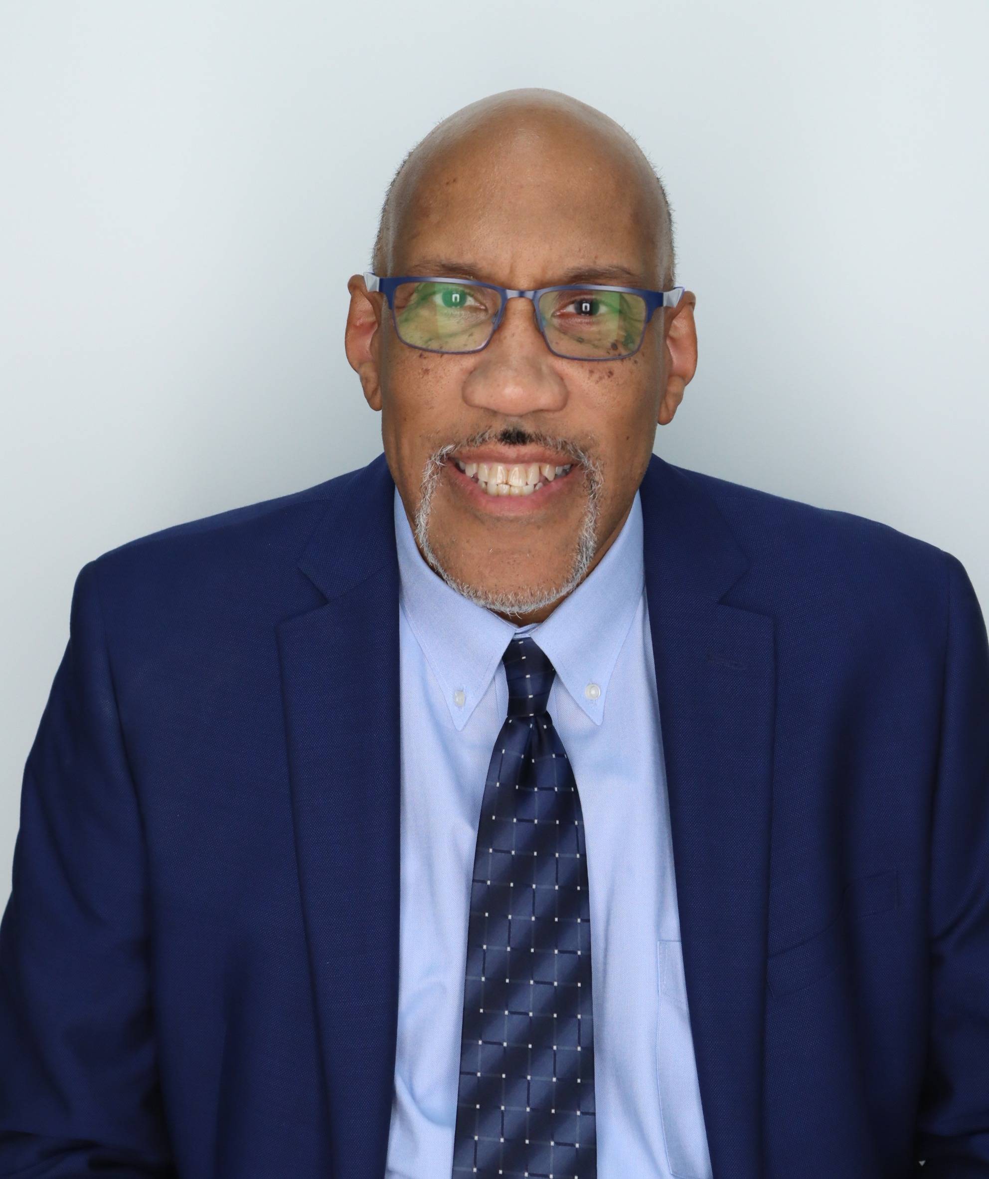 Terence Parker headshot, smiling wearing a navy blue suit and baby blue shirt and striped blue tie