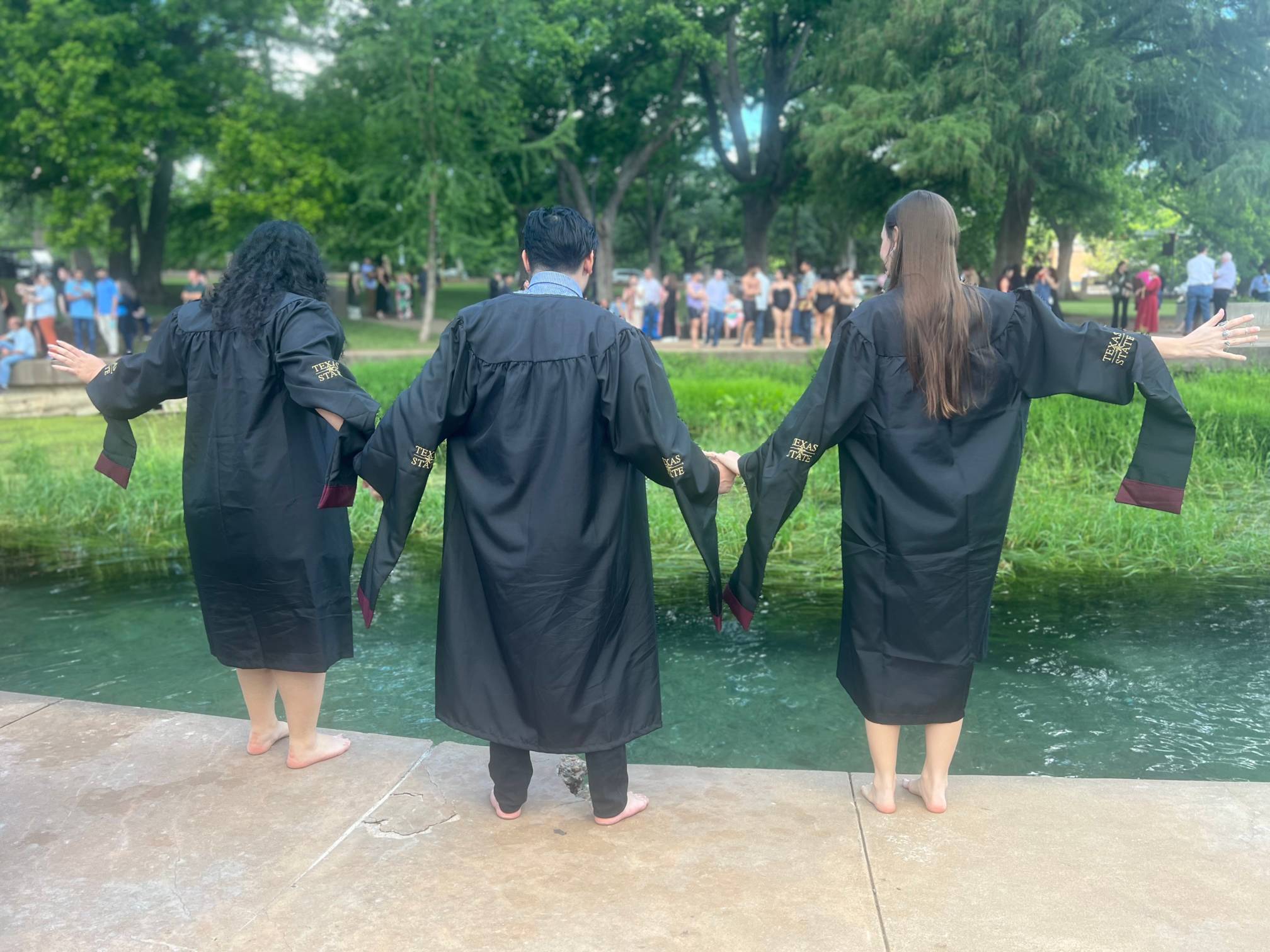 MAPR students Pardis Lahouti, Brandon Thint, and Olivia Teasdale continue the tradition of jumping into the San Marcos River after graduation to celebrate commencement