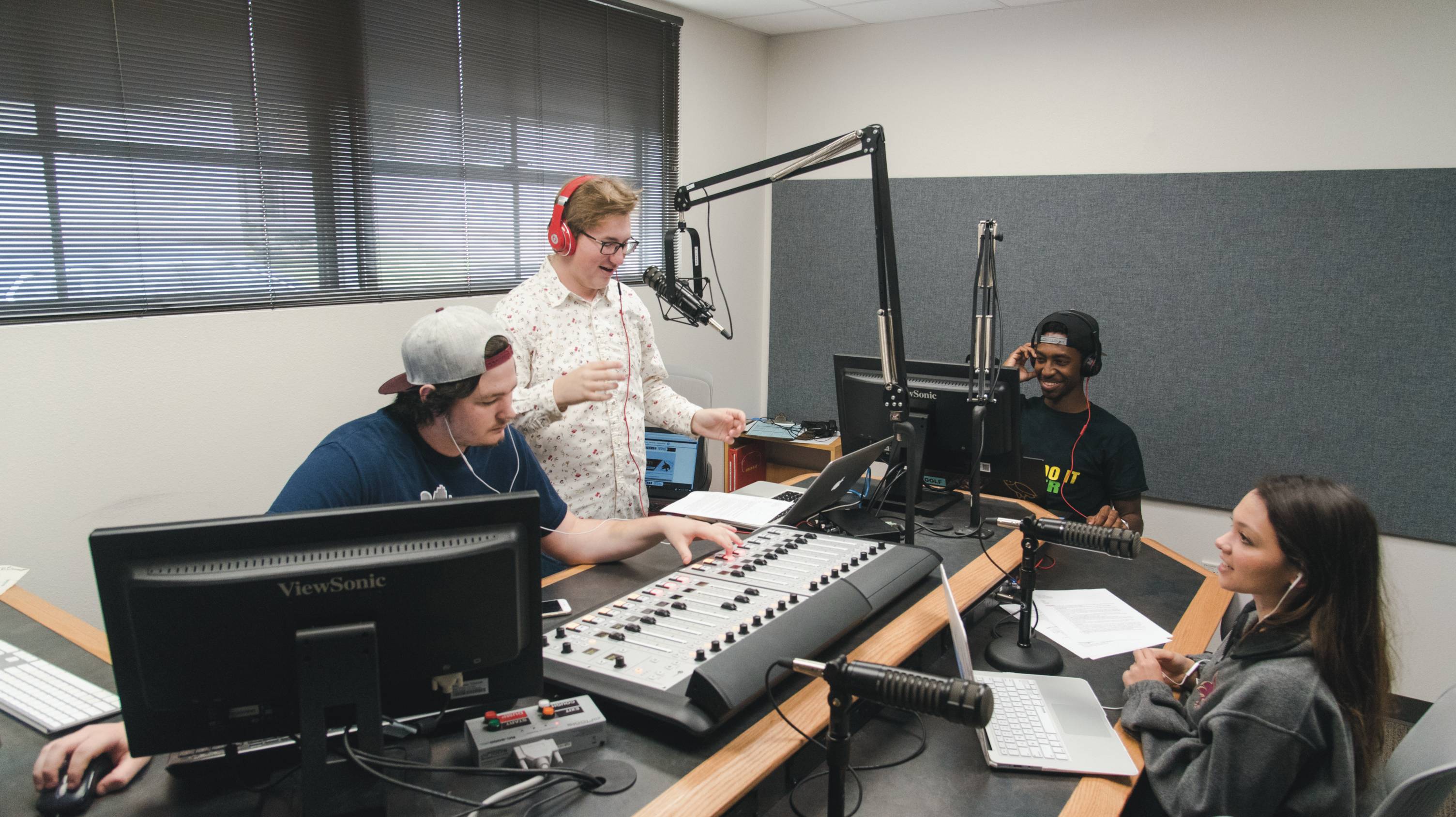 Photo of students participating in a radio show or podcast.
