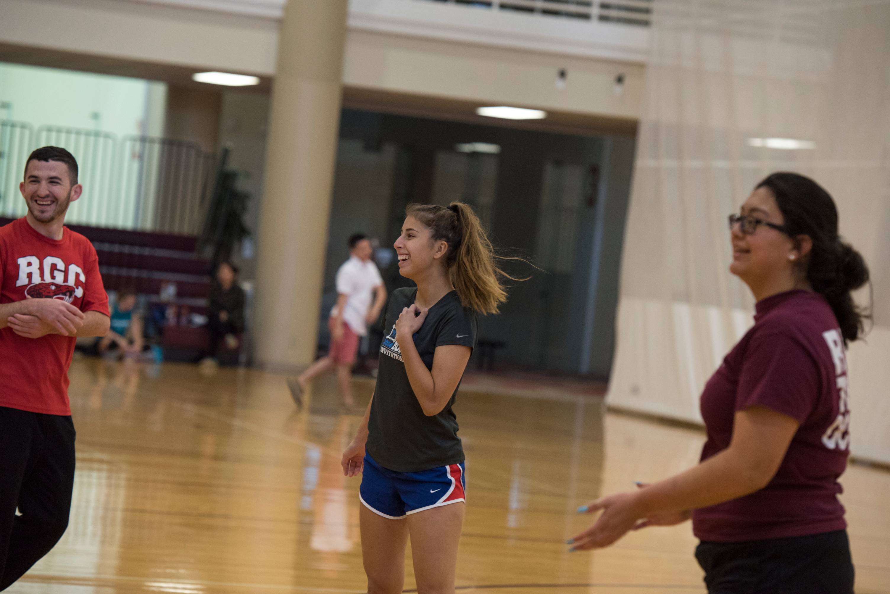 Three students playing in a volleyball court