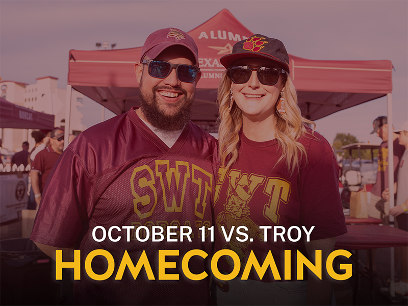 Two people at an alumni tailgate wearing SWT shirts with text reading October 11 vs. Troy, homecoming