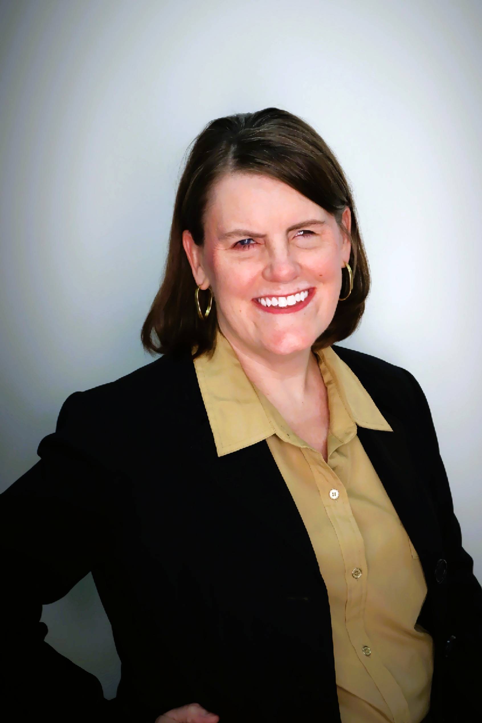 Kathryn Weiser headshot, smiling wearing a gold colored shirt and black blazer.