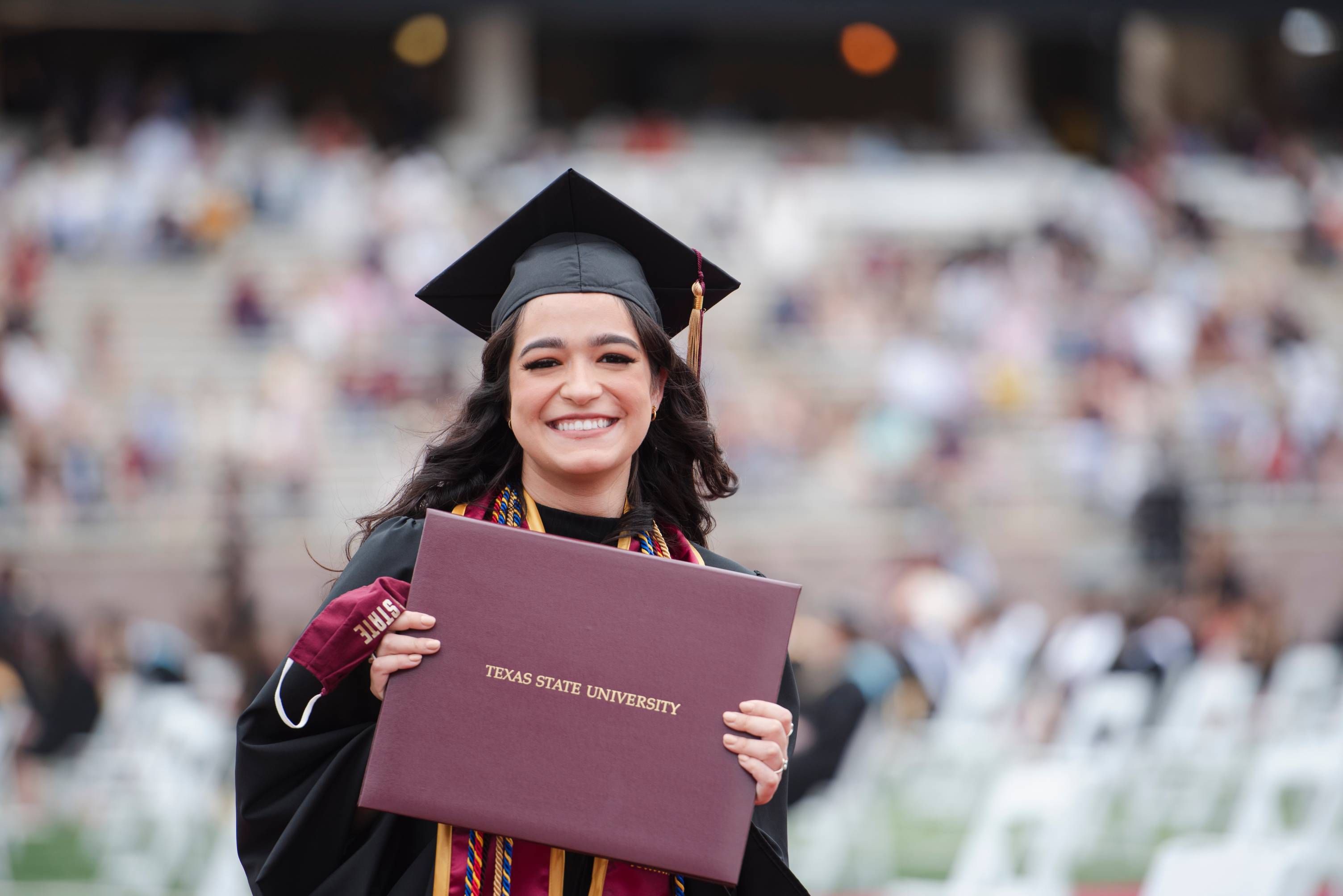 Photo of a student holding a degree at graduation.