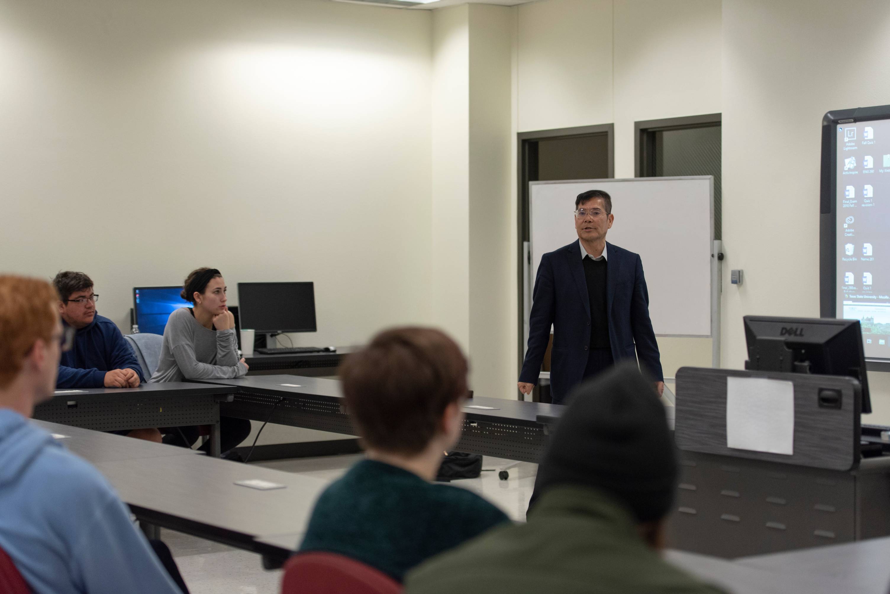 Professor standing in front of class of students.