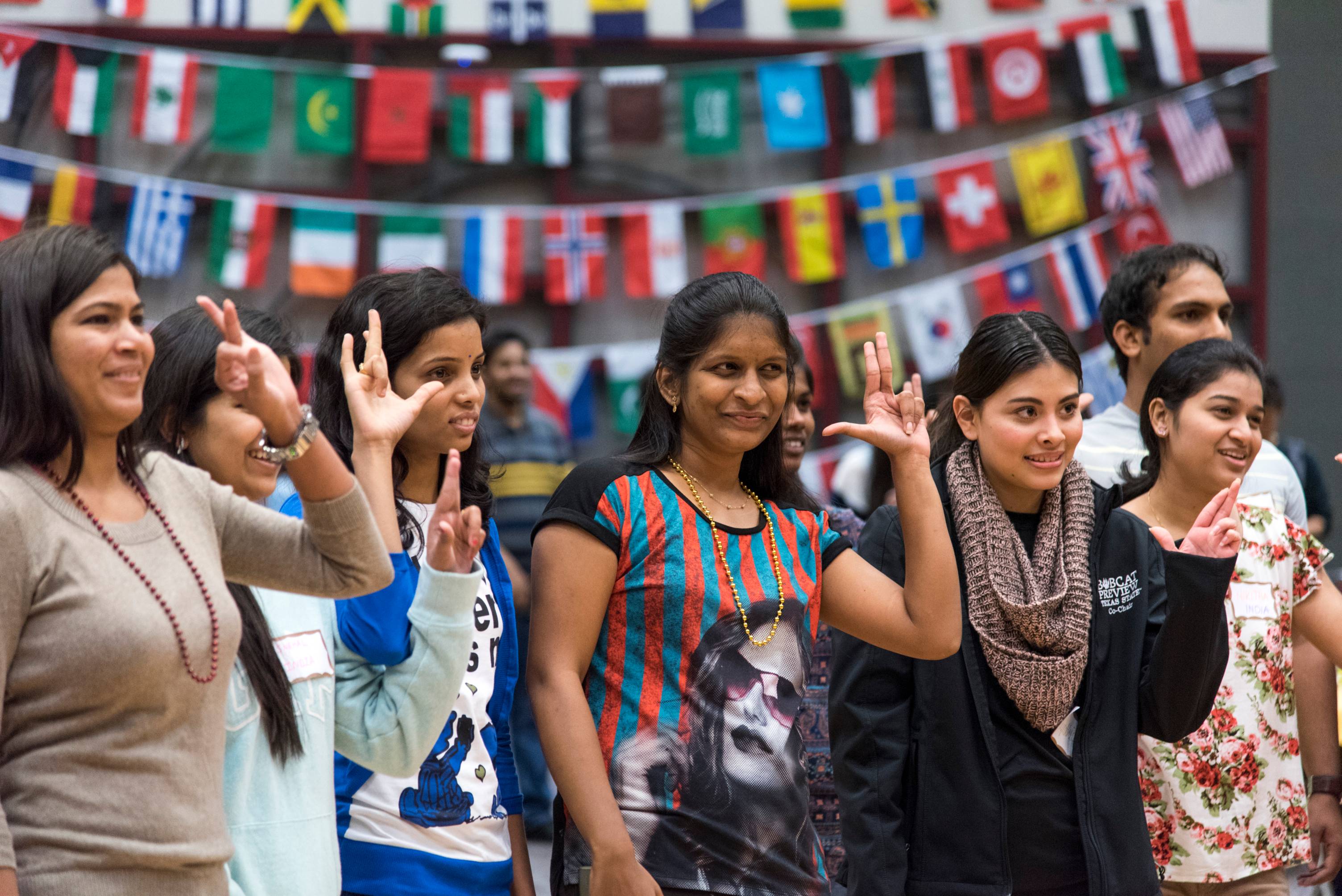 A photo of a group of students posing in front of various international flags