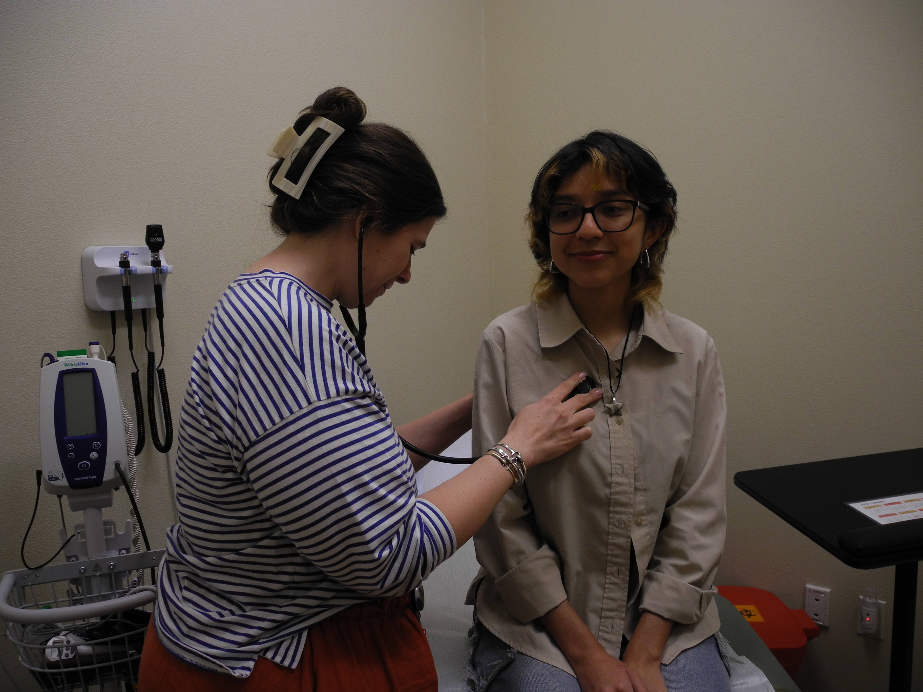 A nurse giving a student a medical exam