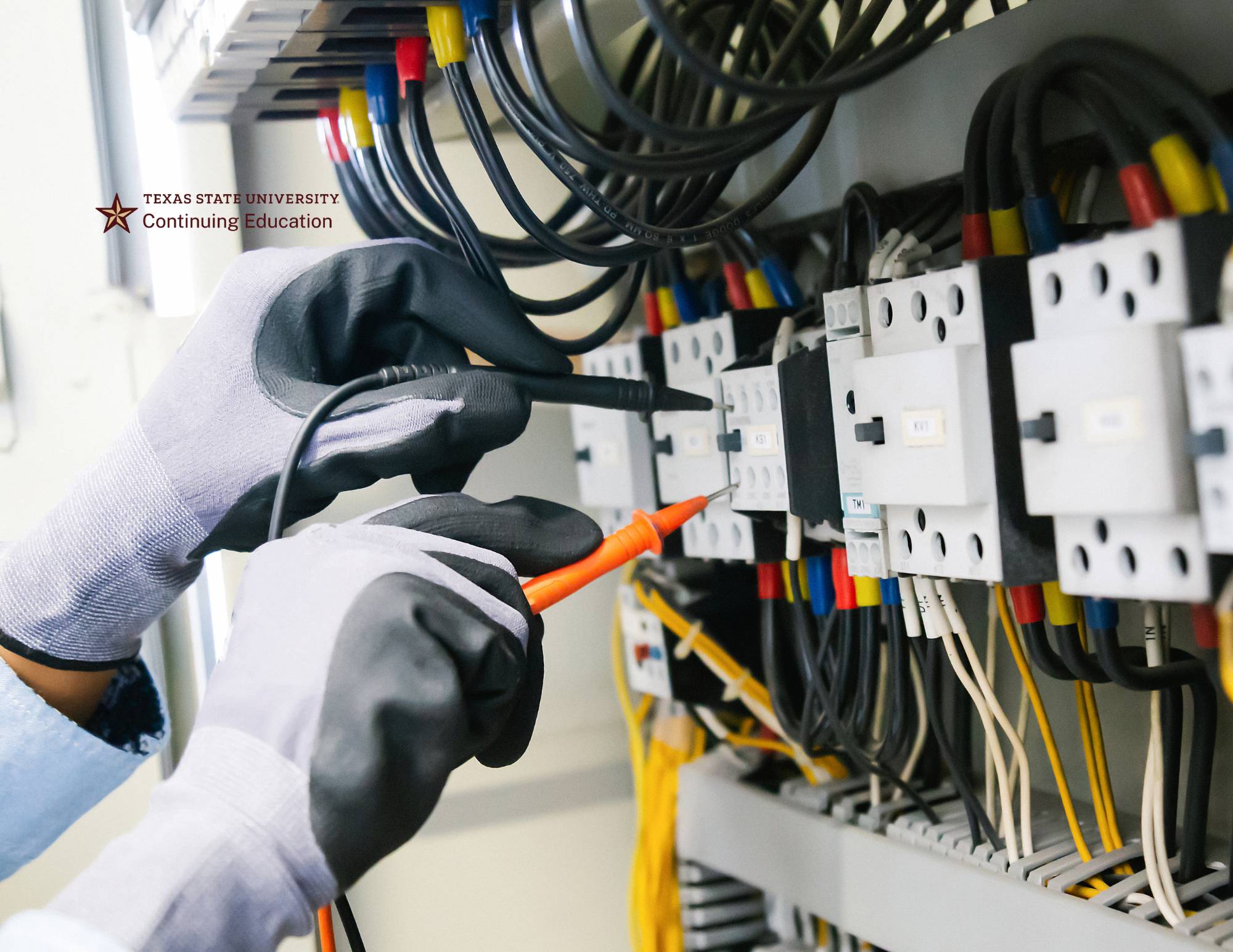 two hands monitoring electrical output of a bank of wires and switchboxes