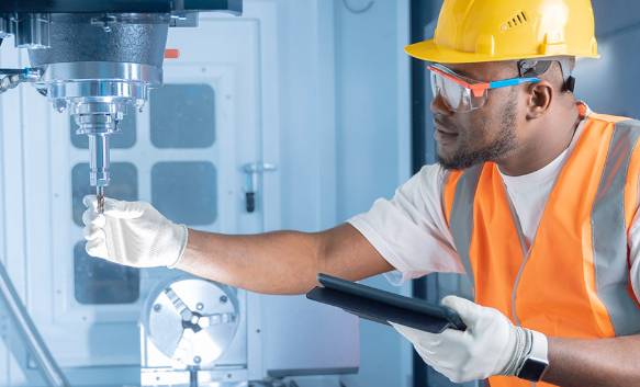 a cnc machinist in white gloves inspecting a drill bit