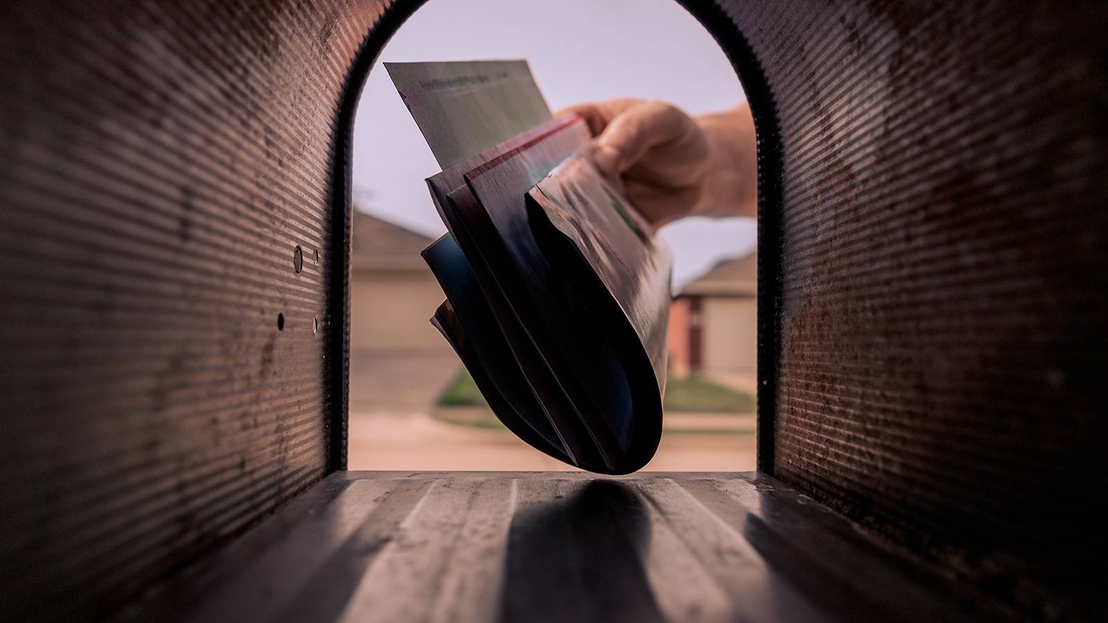 person's hand grabbing mail from the mailbox