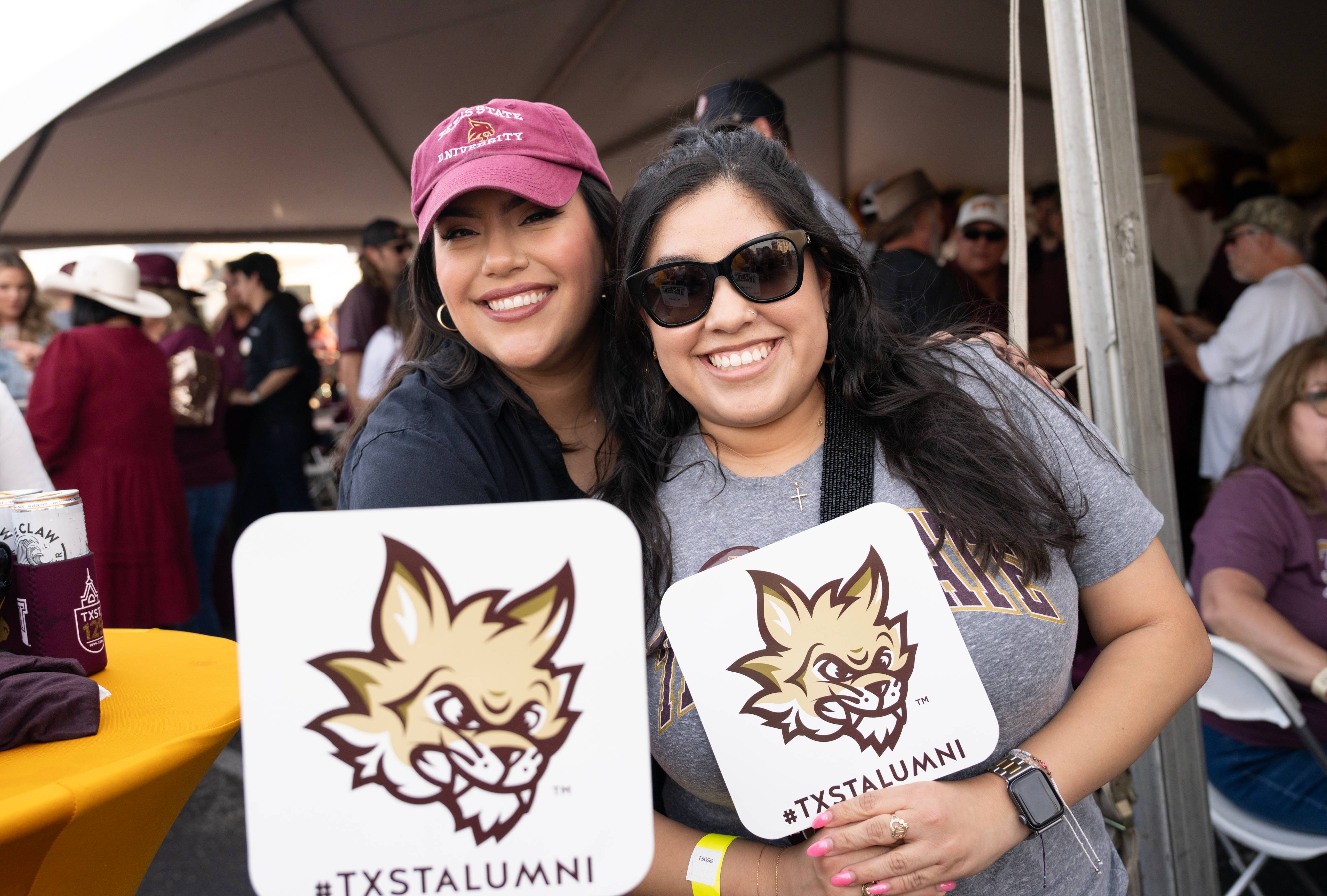 Alumni Social - Two ���Ҵ�ý Alumni holding up ���Ҵ�ý Alumni Paper Fans