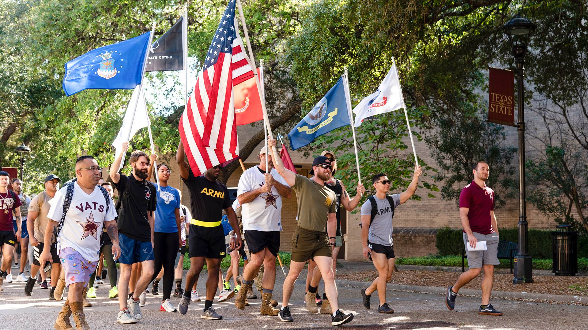veterans walking on a college campus holding flags