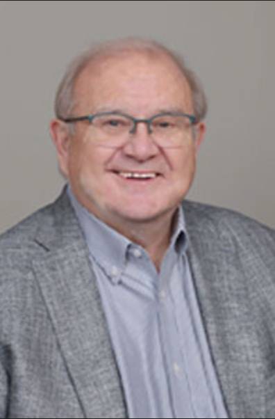 portrait of an old man with glasses in a silver shirt and grey suit coat