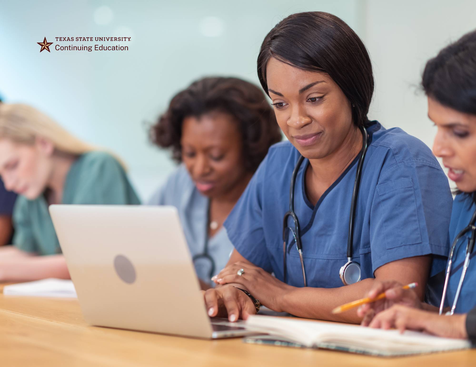 nurses learning at a table and reading a laptop