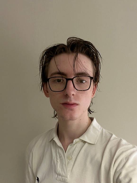 man with glasses, white polo shirt, light-colored wall behind him