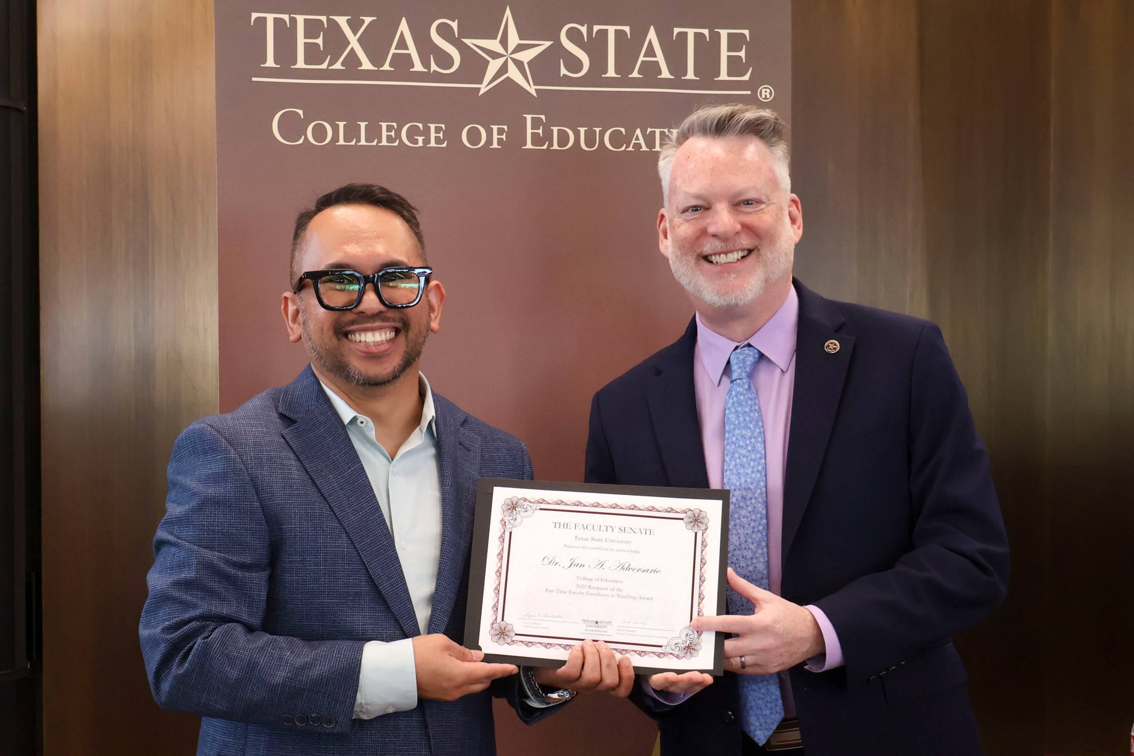 two men posing for photo holding award certificate between them