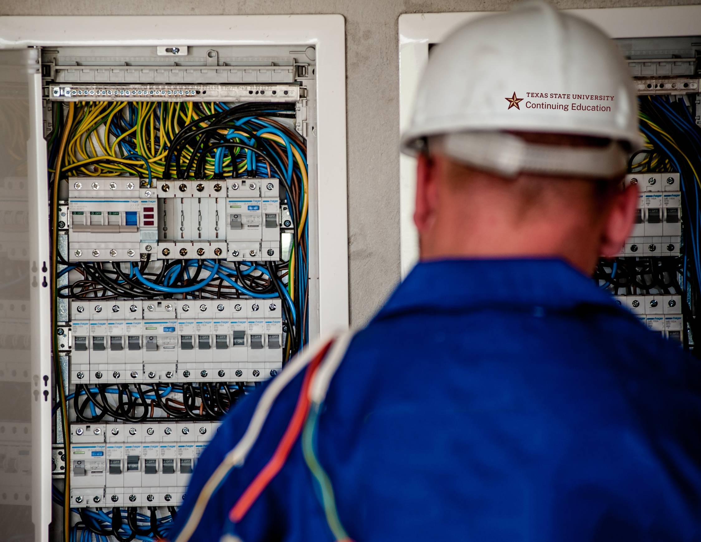 an electrician in a white hard hat reviewing a power box