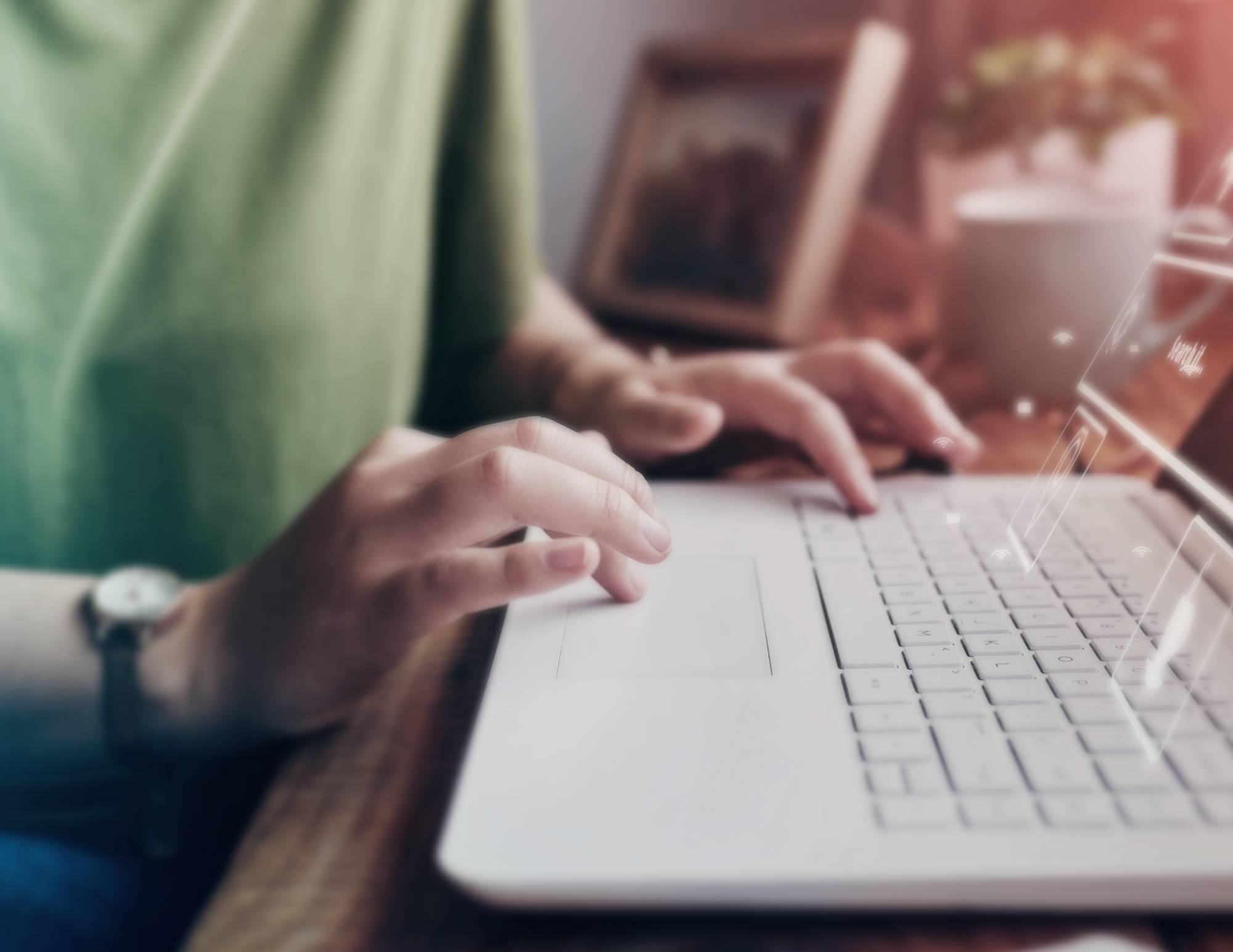 man in green shirt typing on white laptop