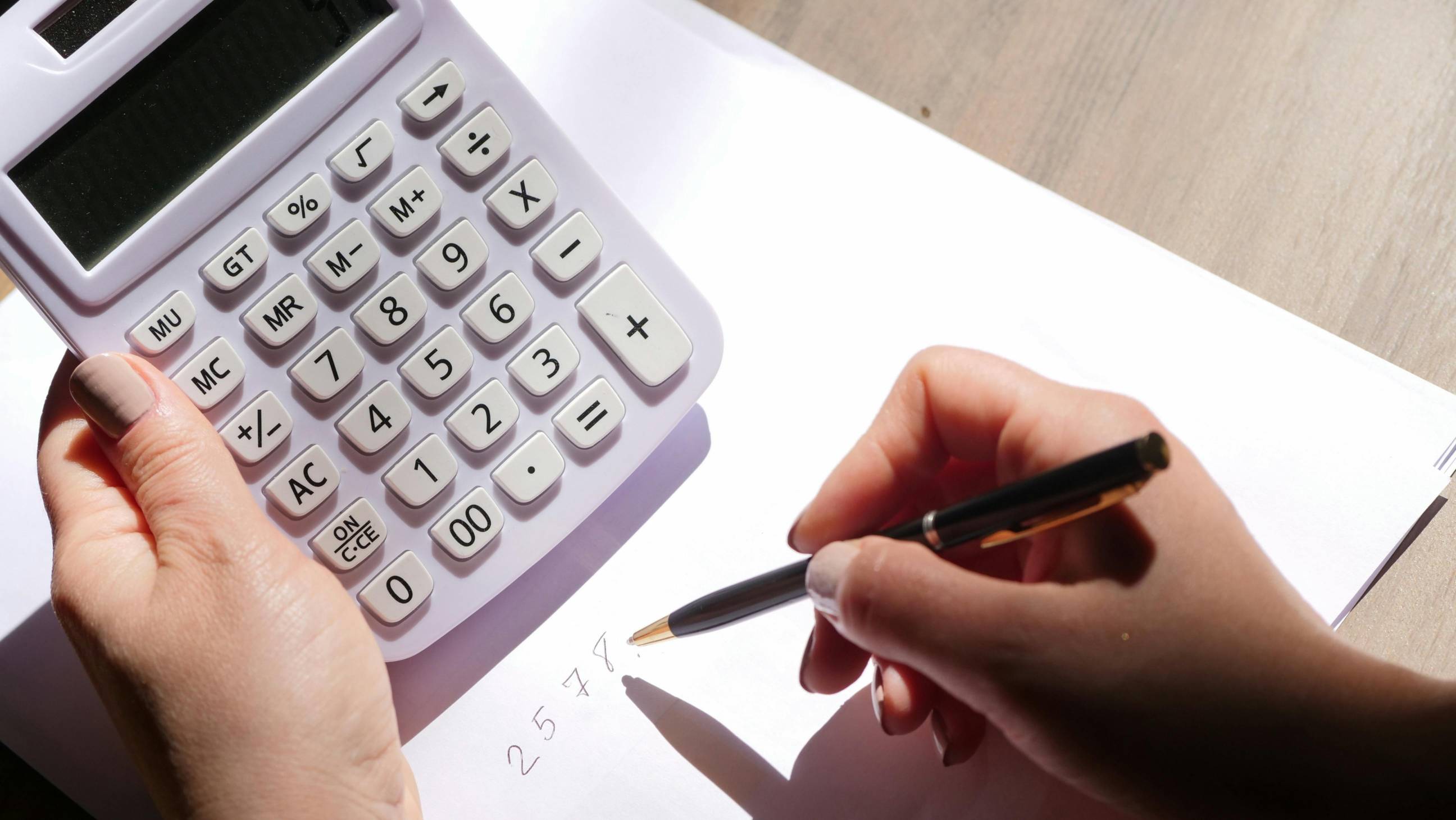 Person holding a calculator and a pen
