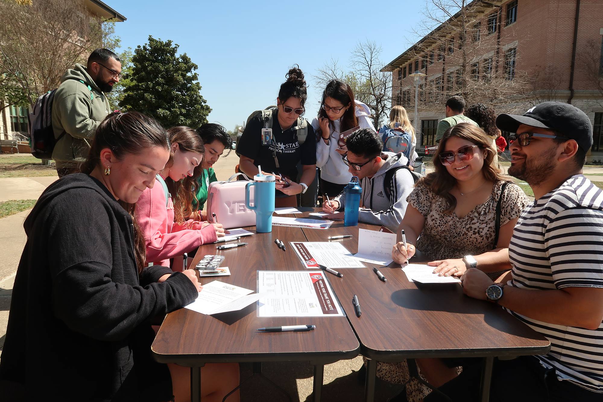 Students at a table writing thank you cards to donors at the Round Rock Campus