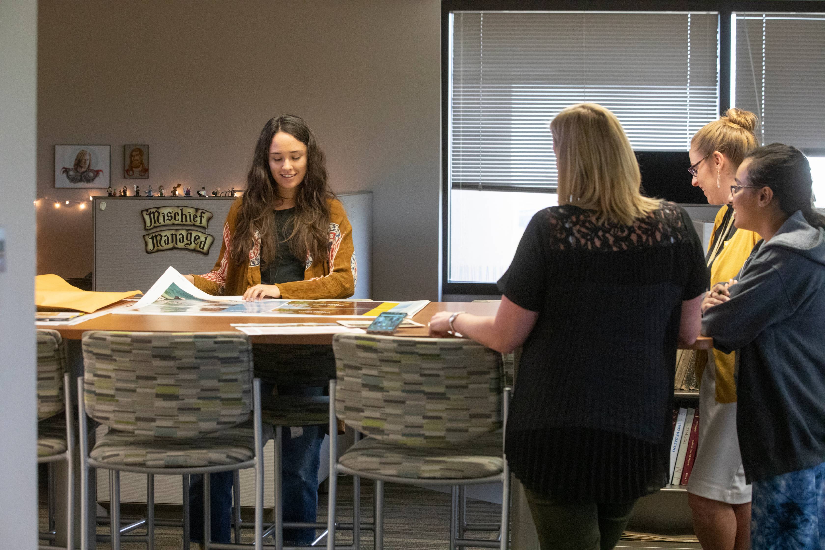 four women gathered around a table looking at marketing materials